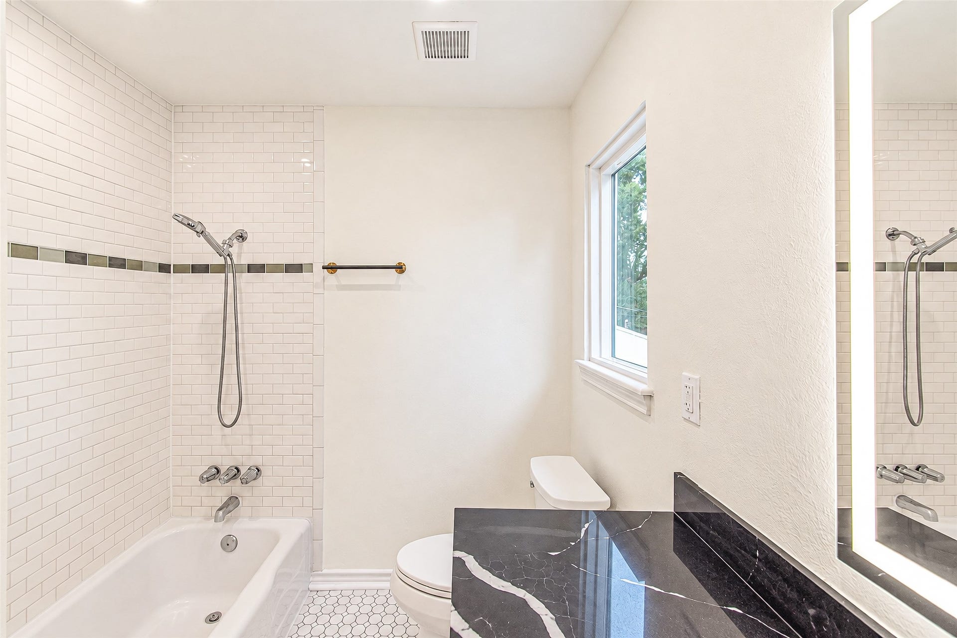 10610 Overbrook Lane, Houston, TX 77042 Experience luxury in the primary bath, featuring sleek subway tiles, a chic black quartz countertop, and abundant natural light for a serene retreat.
