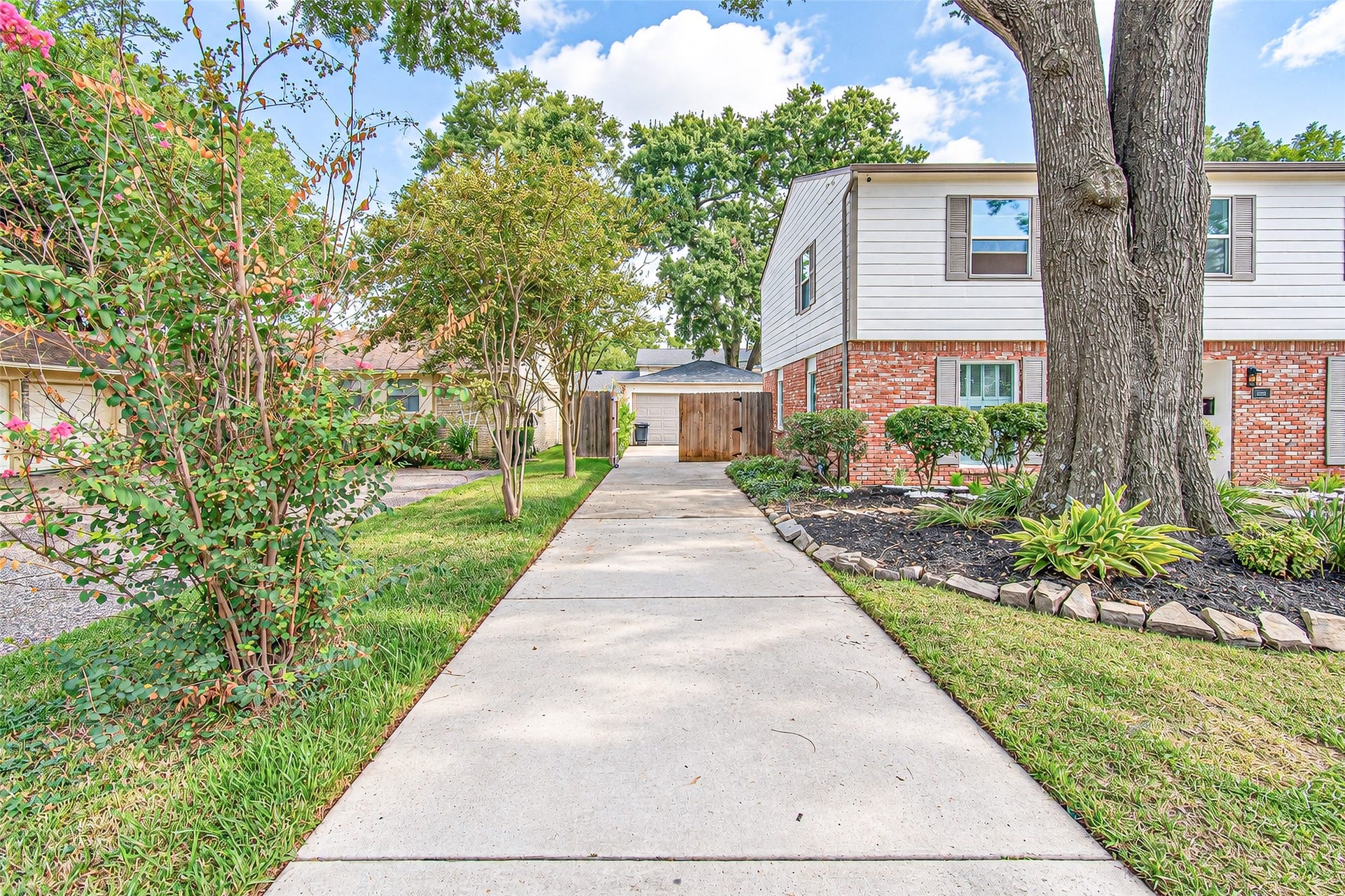 10610 Overbrook Lane, Houston, TX 77042 Charming two-story home with classic brick exterior, framed by mature trees and lush landscaping, leading to a welcoming front walkway.