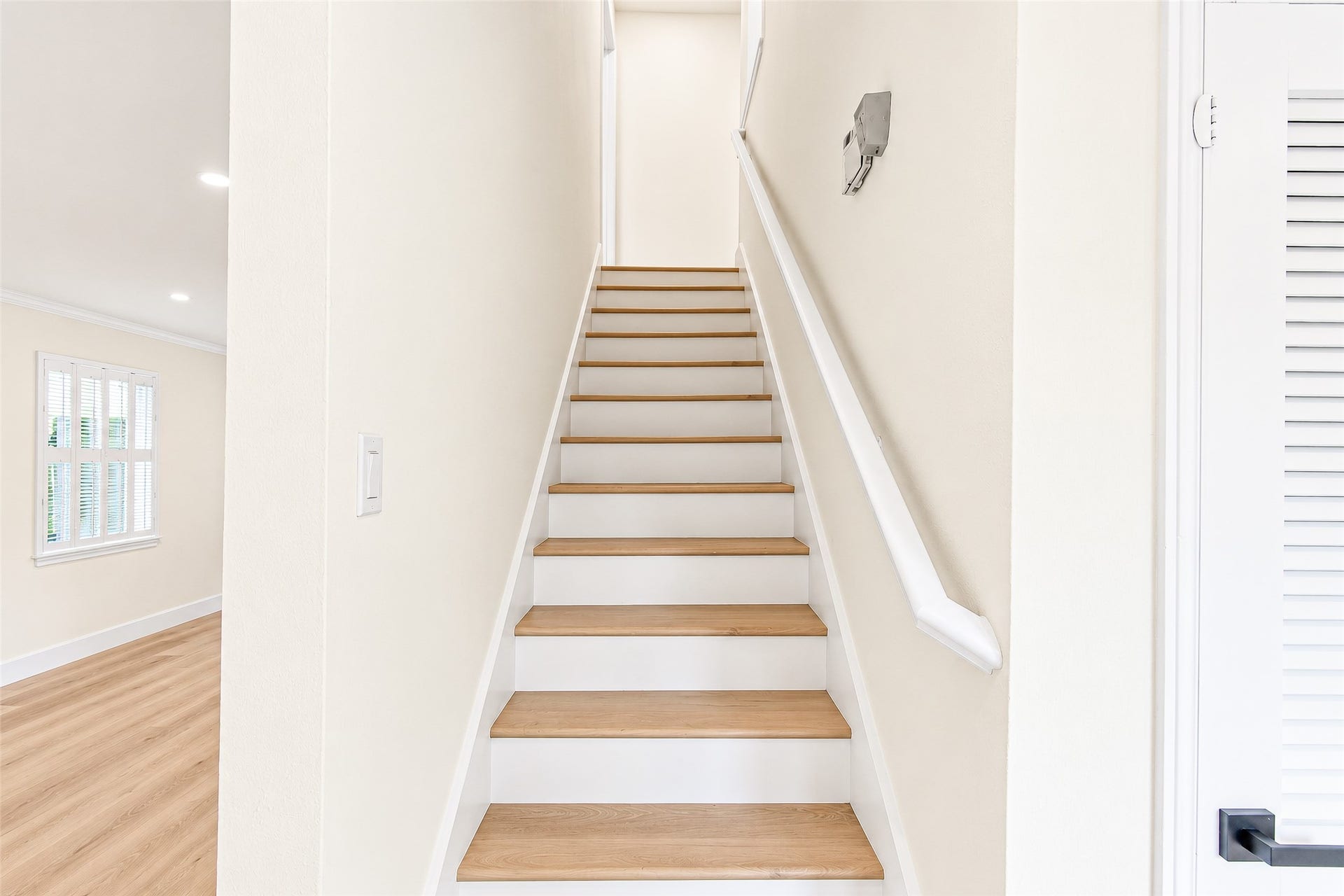 10610 Overbrook Lane, Houston, TX 77042 Bright and inviting staircase with natural vinyl steps leads to the upper level, complemented by fresh white walls and a sleek handrail.
