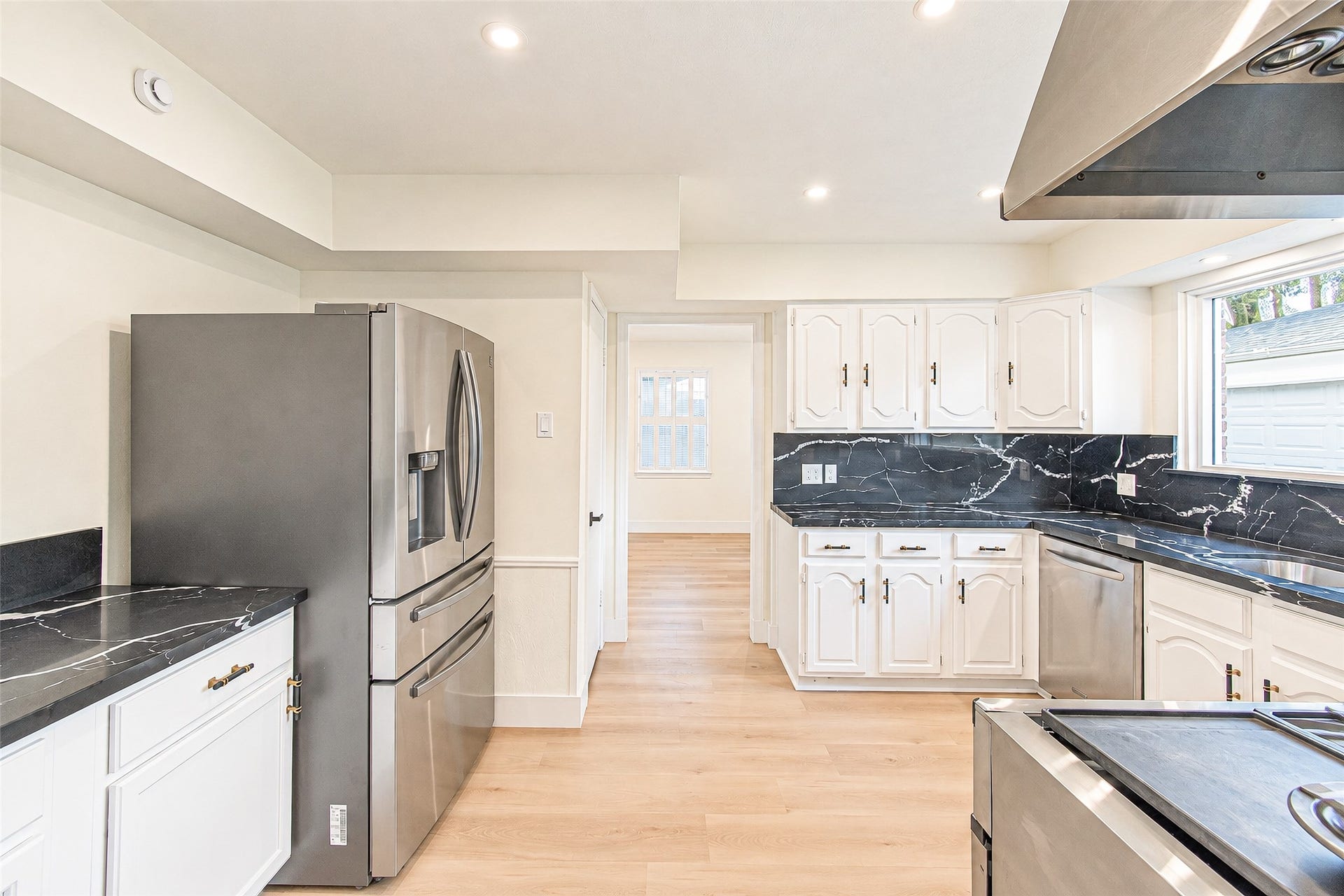10610 Overbrook Lane, Houston, TX 77042 Bright kitchen with sleek stainless steel appliances, elegant black quartz countertops, and ample white cabinetry, offering a perfect blend of style and functionality.