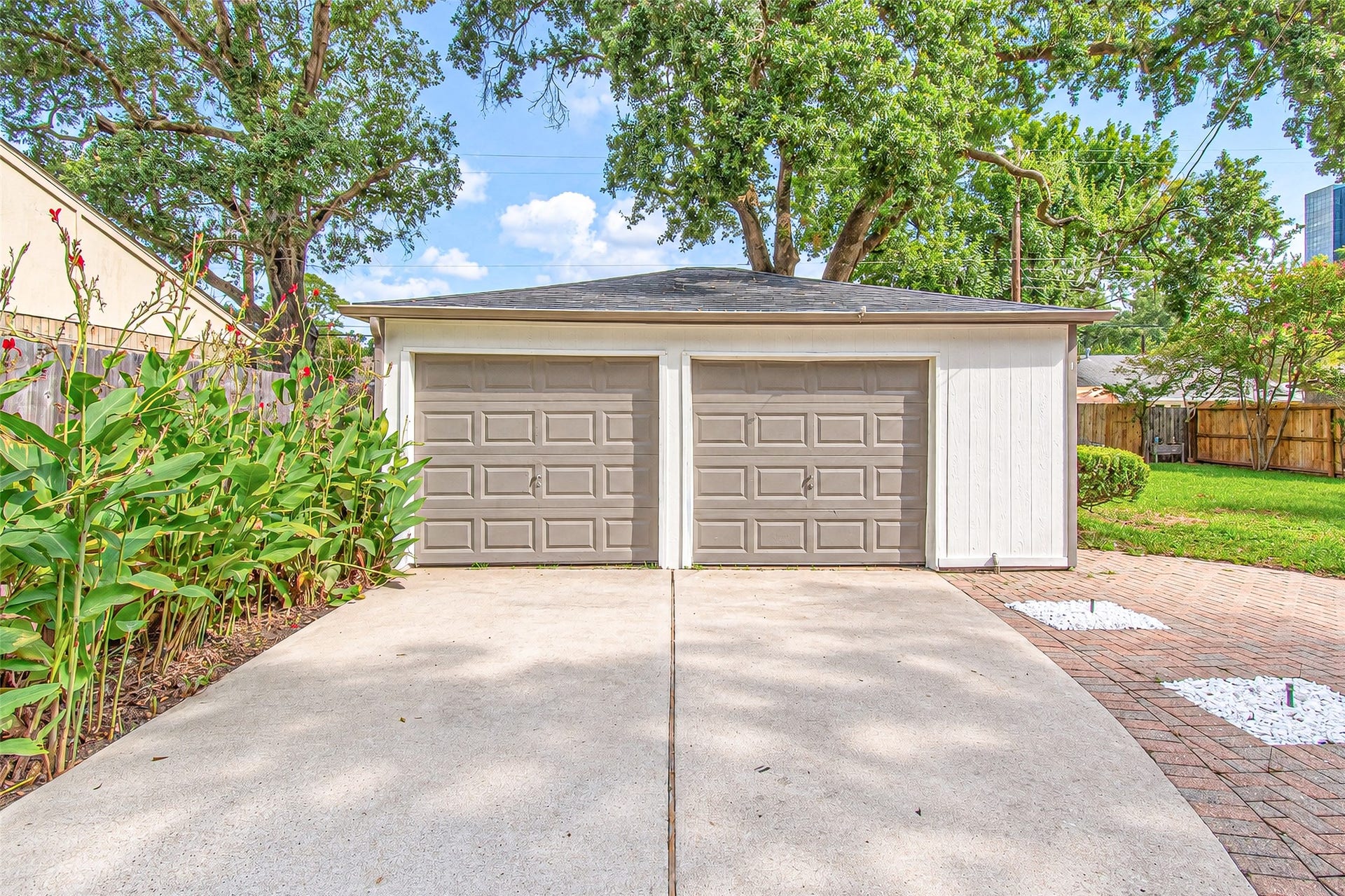 10610 Overbrook Lane, Houston, TX 77042 Spacious double garage with a wide driveway, surrounded by lush greenery and mature trees, offering ample storage and parking space.