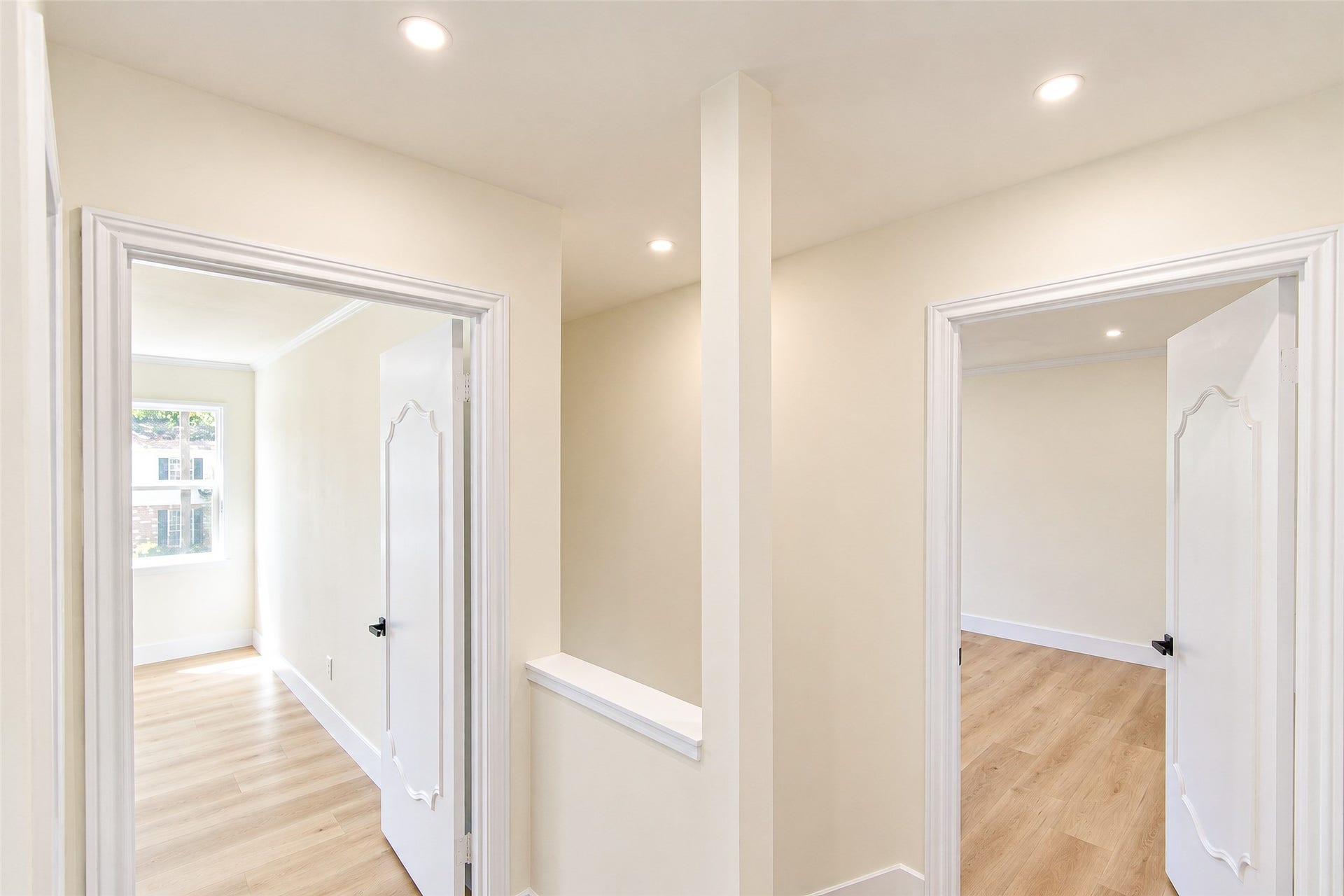 10610 Overbrook Lane, Houston, TX 77042 Bright and inviting hallway with elegant white doors leading to sunlit rooms, featuring light wood flooring and recessed lighting.