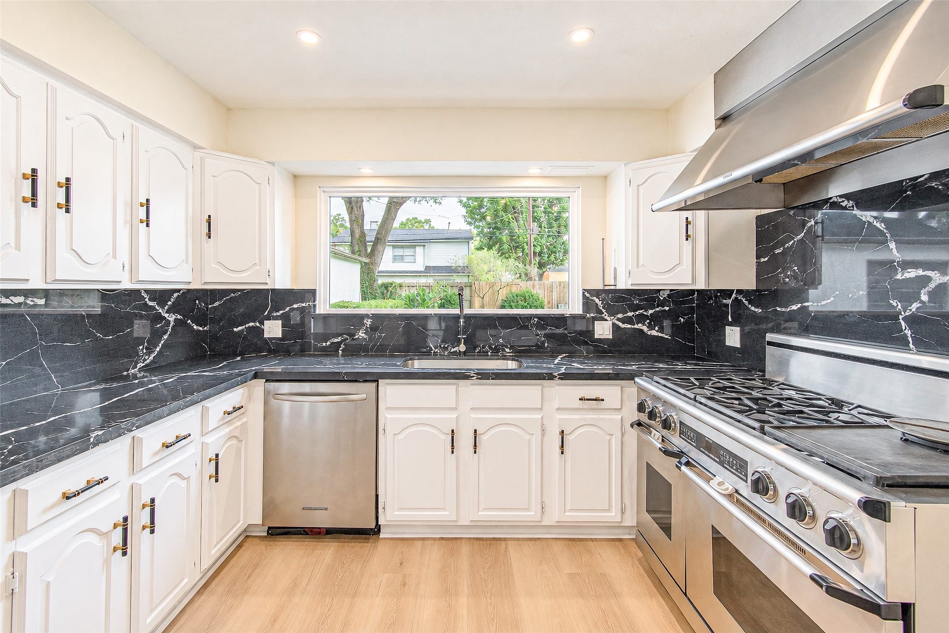 10610 Overbrook Lane, Houston, TX 77042 Modern kitchen featuring sleek black quartz countertops and backsplash, complemented by white cabinetry and high-end stainless steel appliances.