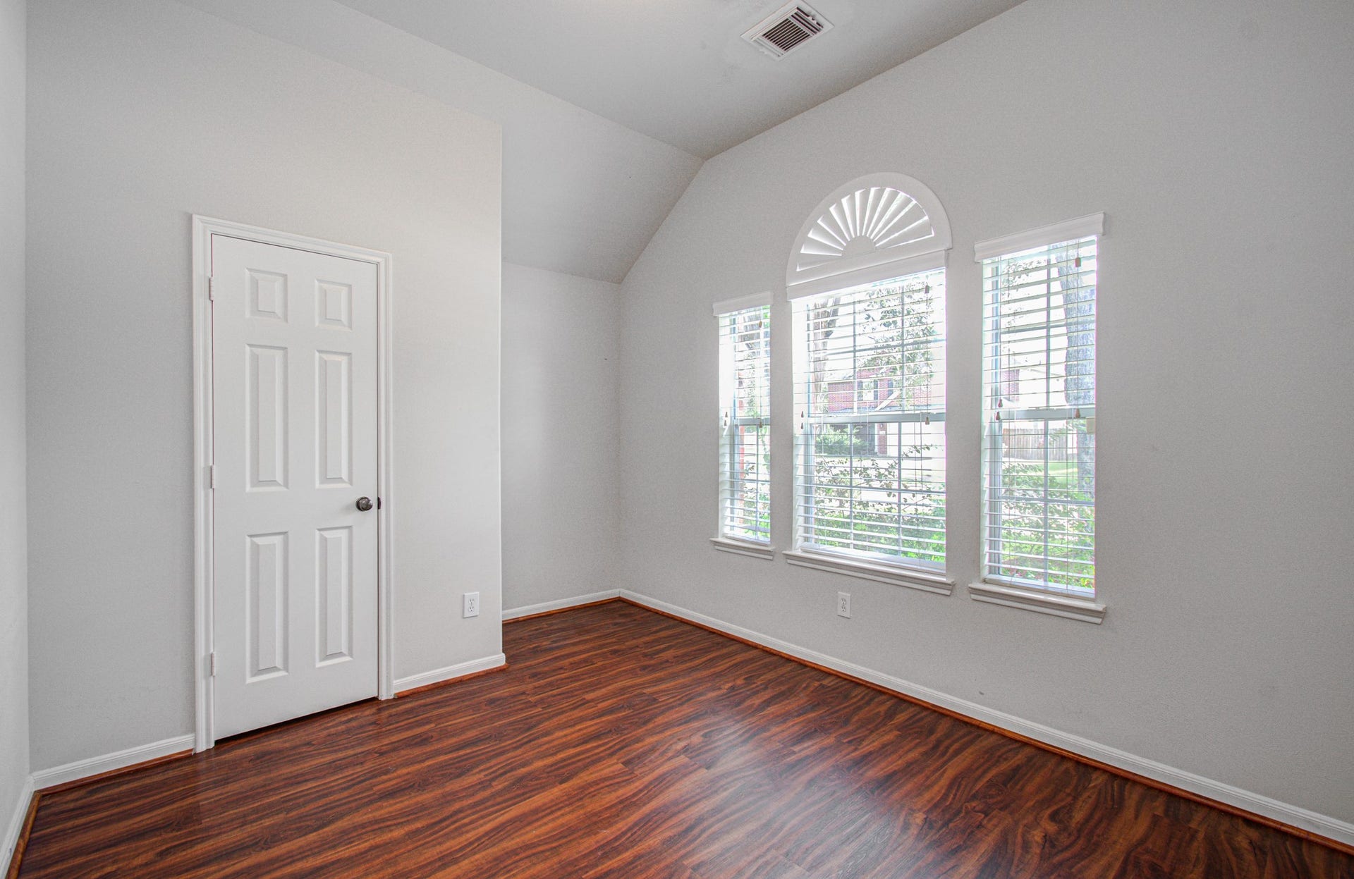 12808 Brook Arbor Court, Pearland, TX 77584 Bright bedroom featuring elegant arched windows and rich wood flooring, and a vaulted ceiling for a cozy and inviting space.