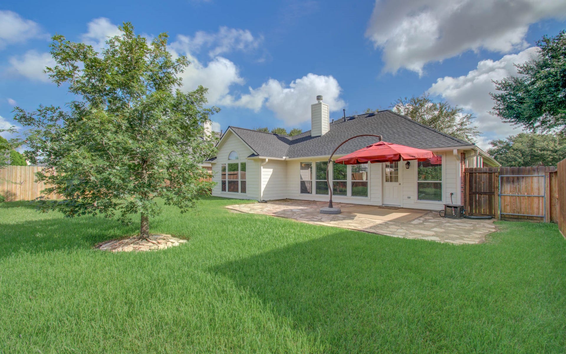 12808 Brook Arbor Court, Pearland, TX 77584 Charming backyard featuring lush green grass and mature trees for added privacy and shade.