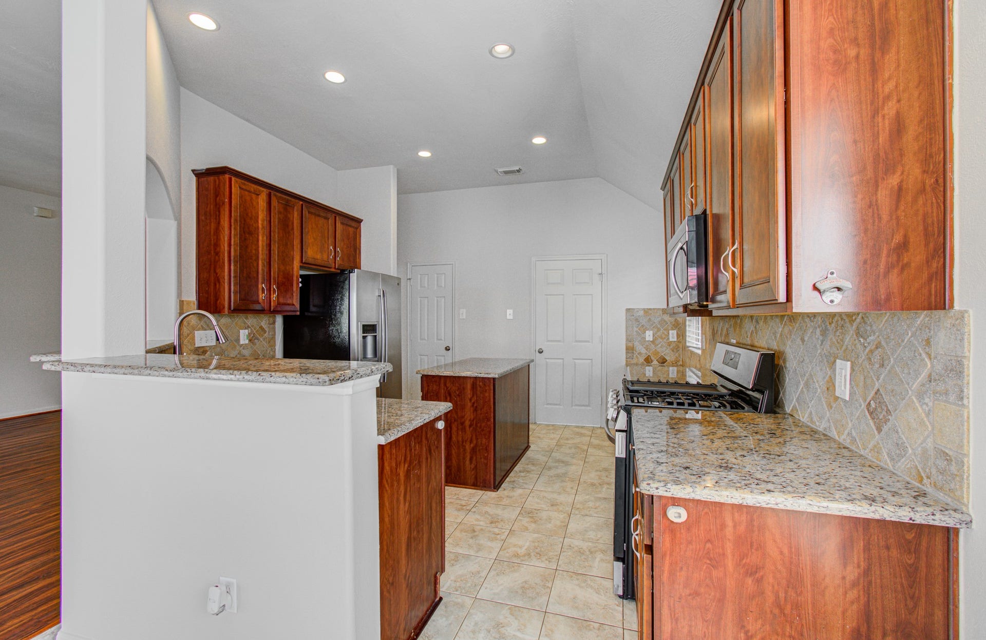 12808 Brook Arbor Court, Pearland, TX 77584 Gracious sized kitchen featuring elegant granite countertops, rich wood cabinetry, and modern stainless steel appliances, accented by a stylish tile backsplash.