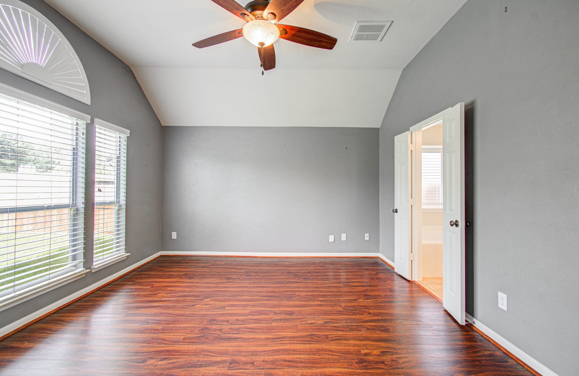 12808 Brook Arbor Court, Pearland, TX 77584 Primary bedroom with vaulted ceilings, rich wood flooring, and abundant natural light from large windows.
