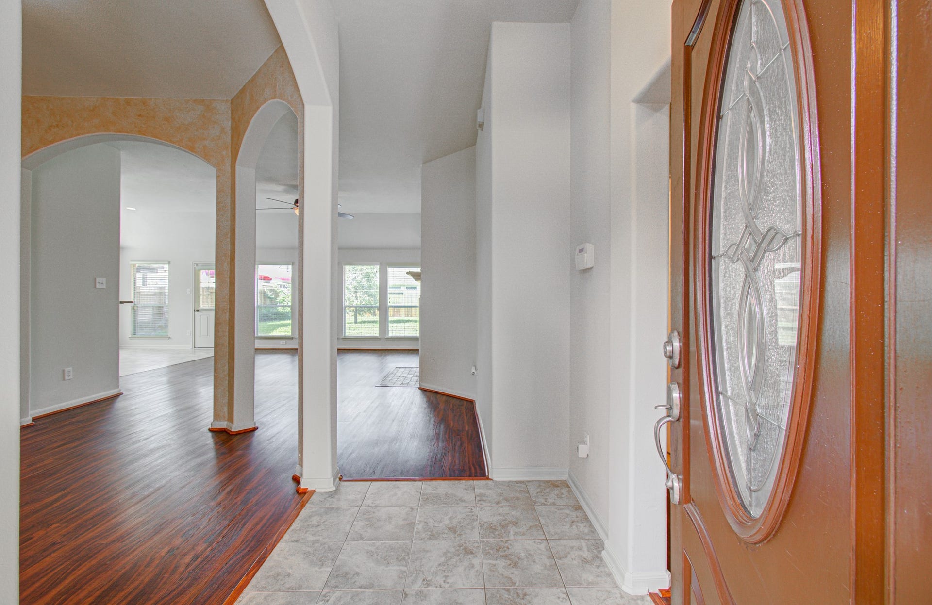 12808 Brook Arbor Court, Pearland, TX 77584 Inviting entryway with elegant tile flooring and a warm wooden door, leading into an open living area featuring rich wood floors and ample natural light.