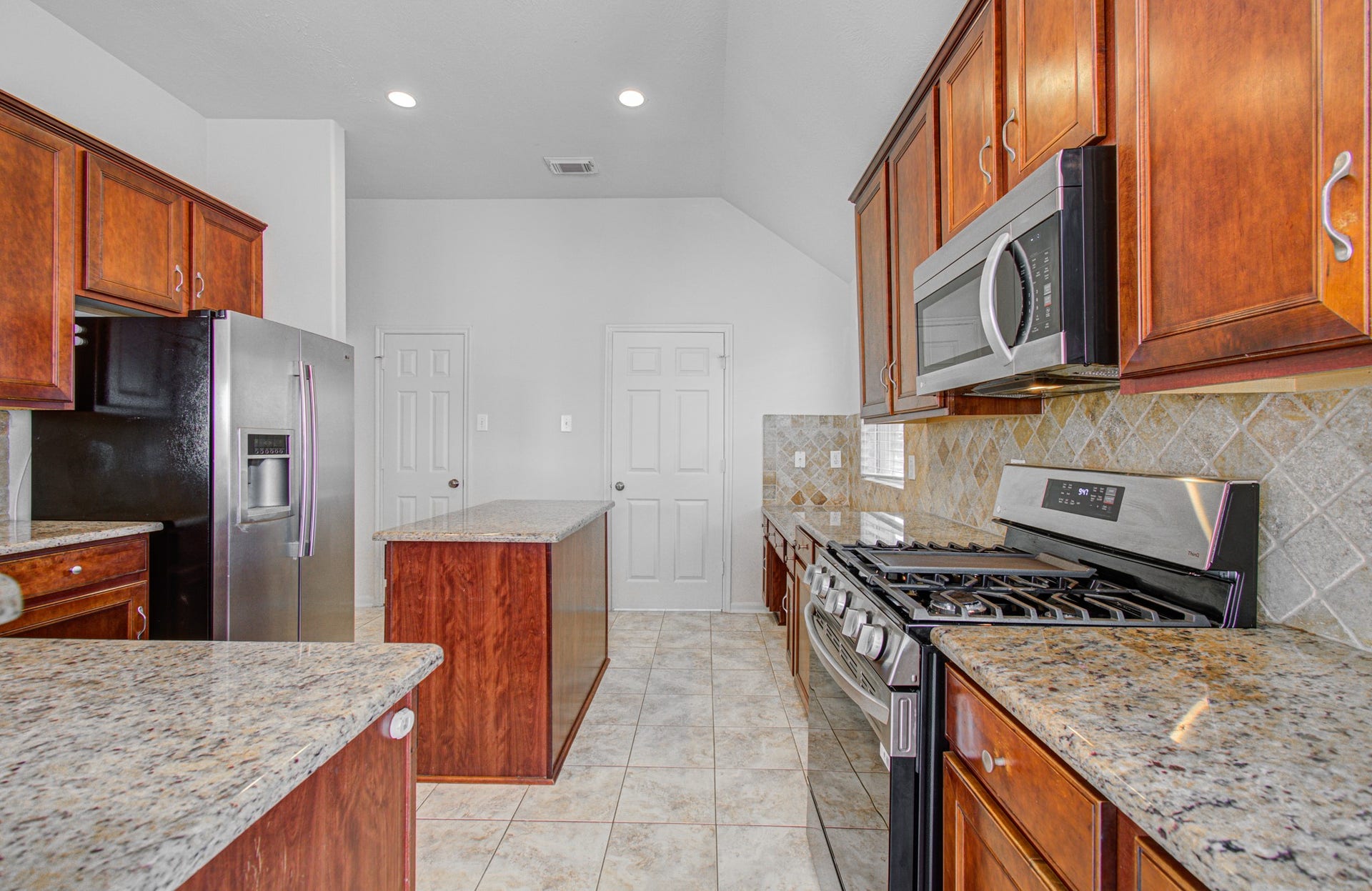 12808 Brook Arbor Court, Pearland, TX 77584 Spacious kitchen with elegant granite countertops, rich wooden cabinetry, and modern stainless steel appliances, including a gas stove and side-by-side refrigerator.