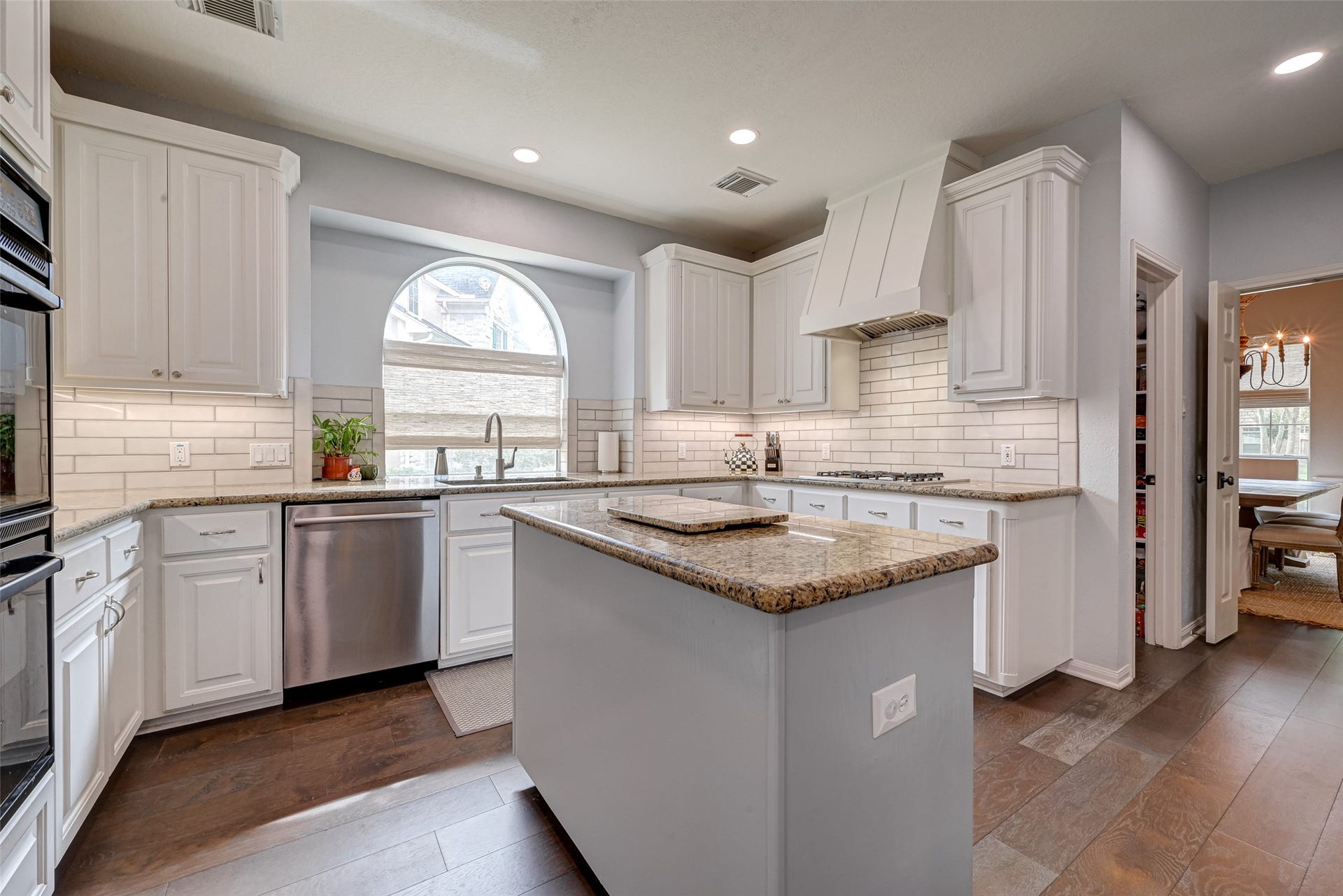 7707 Stone Arbor Drive, Sugar Land, TX 77479 Welcome to a Kitchen with room to actually cook! The spacious layout offers abundant cabinetry and granite counter space, a center island, updated recessed lighting, under-cabinet lighting, and a classic subway tile backsplash. The large arched window over the sink brings in natural light and adds architectural character.