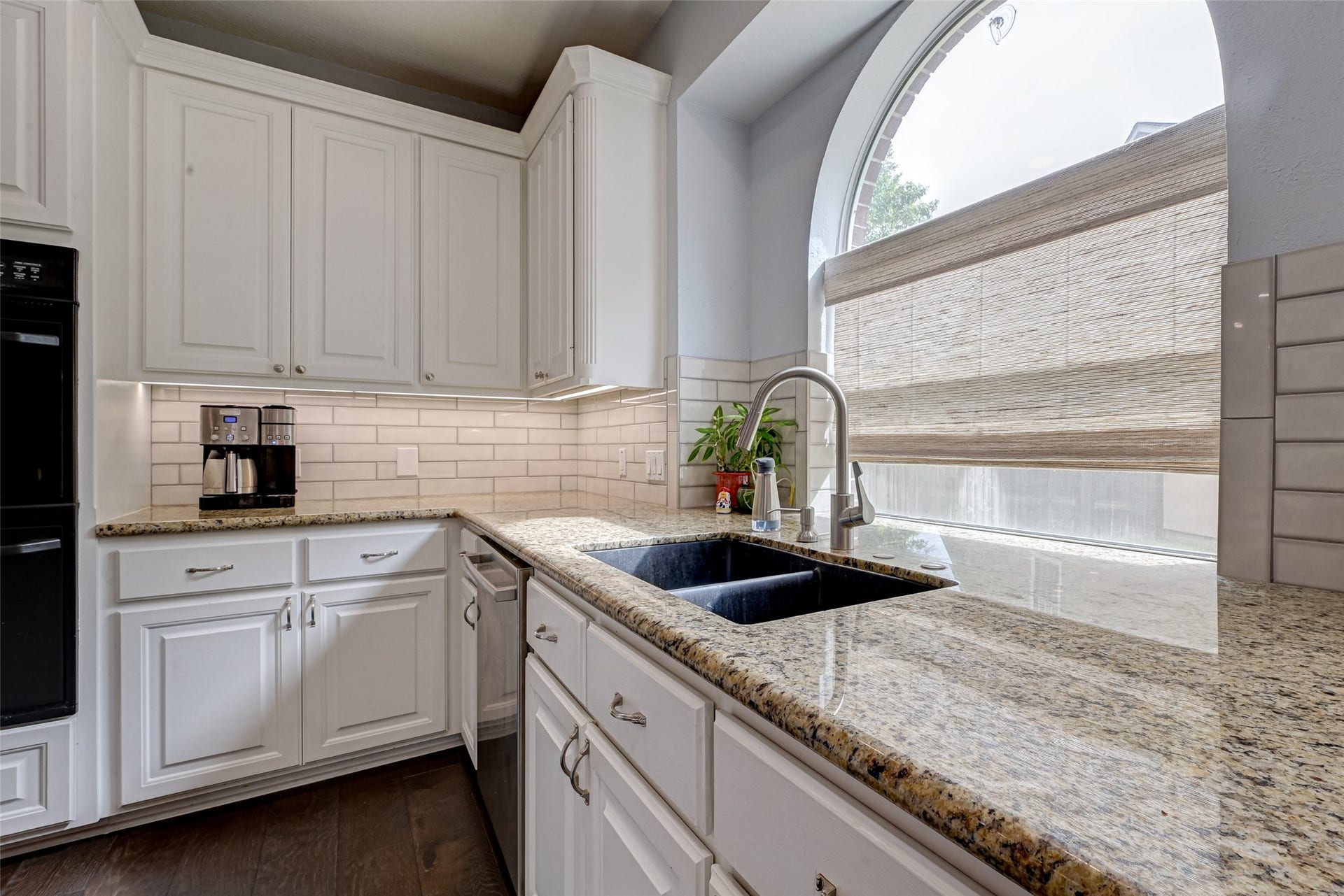 7707 Stone Arbor Drive, Sugar Land, TX 77479 Even doing dishes comes with a view! The large arched window creates a beautiful focal point above the double composite sinks while bringing natural light into the Kitchen. Granite counters provide plenty of workspace on both sides, with extensive cabinetry below and the stainless steel dishwasher conveniently positioned nearby.