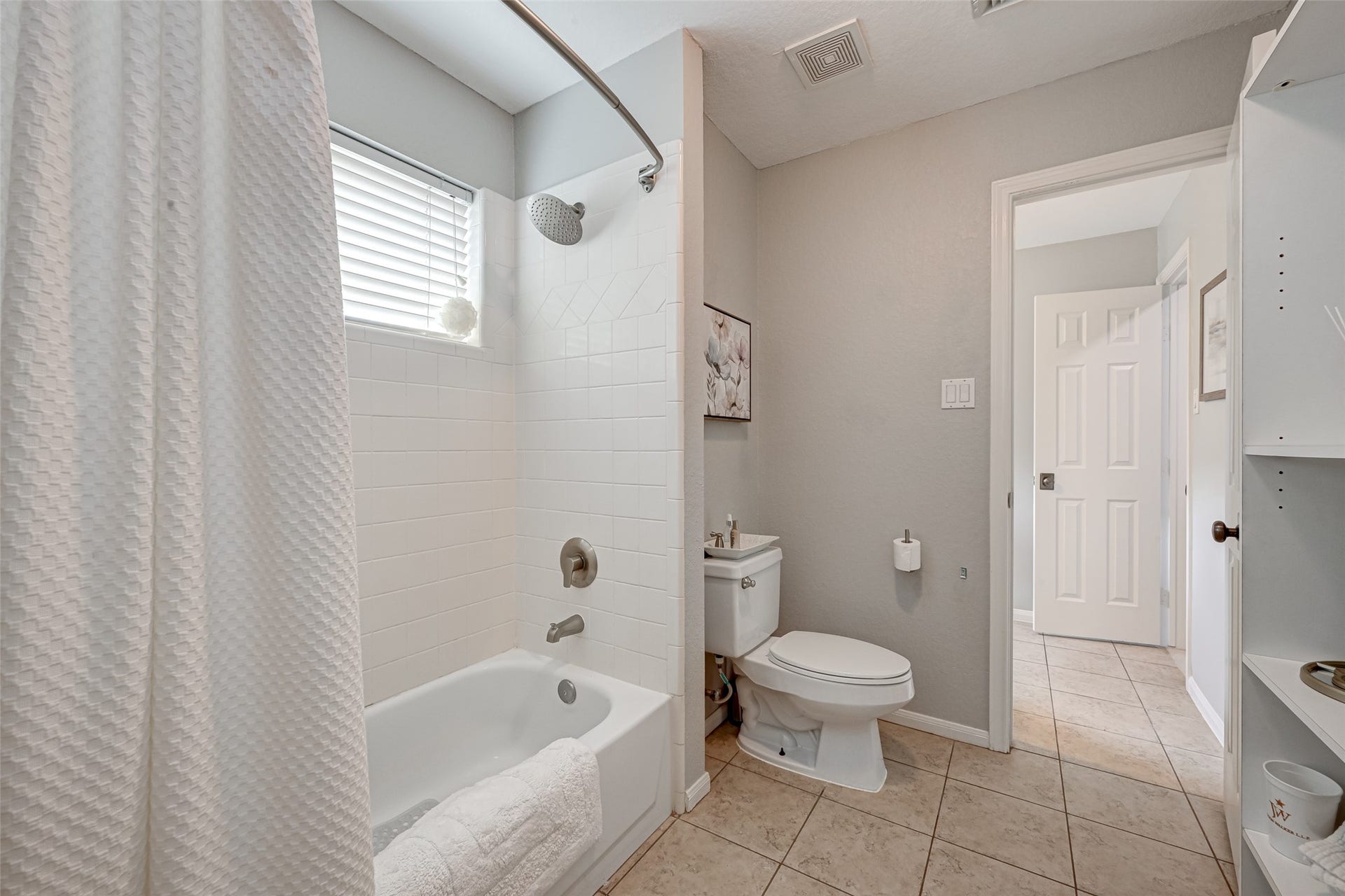 7707 Stone Arbor Drive, Sugar Land, TX 77479 The shared portion of the Jack & Jill bath features a tub/shower combination with tiled surround, commode & additional storage. A window brings in natural light, while the thoughtful layout keeps the bathing area separate from the individual bedroom vanitiesespecially convenient on busy mornings!