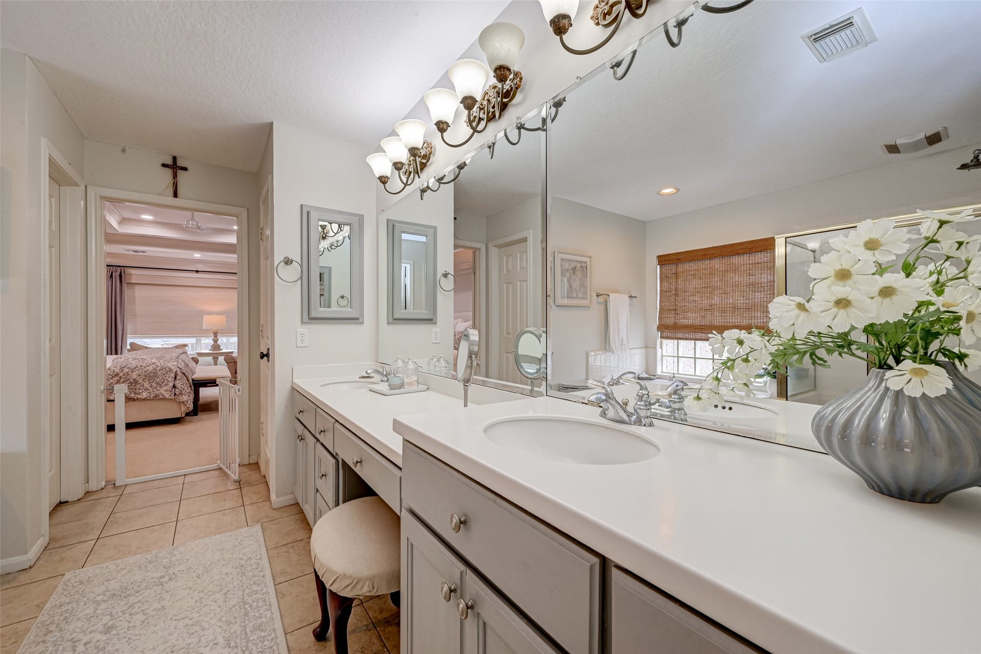 7707 Stone Arbor Drive, Sugar Land, TX 77479 No fighting for counter space here! The vanity stretches nearly the length of the room with 2 sinks set at comfortable vanity height, abundant drawers & cabinetry, and generous counter space. A dedicated makeup area with convenient knee space provides a comfortable spot to sit while getting ready. Additional linen closet + private water closet with commode add storage & privacy, while this view shows the easy connection back to the primary bedroom.