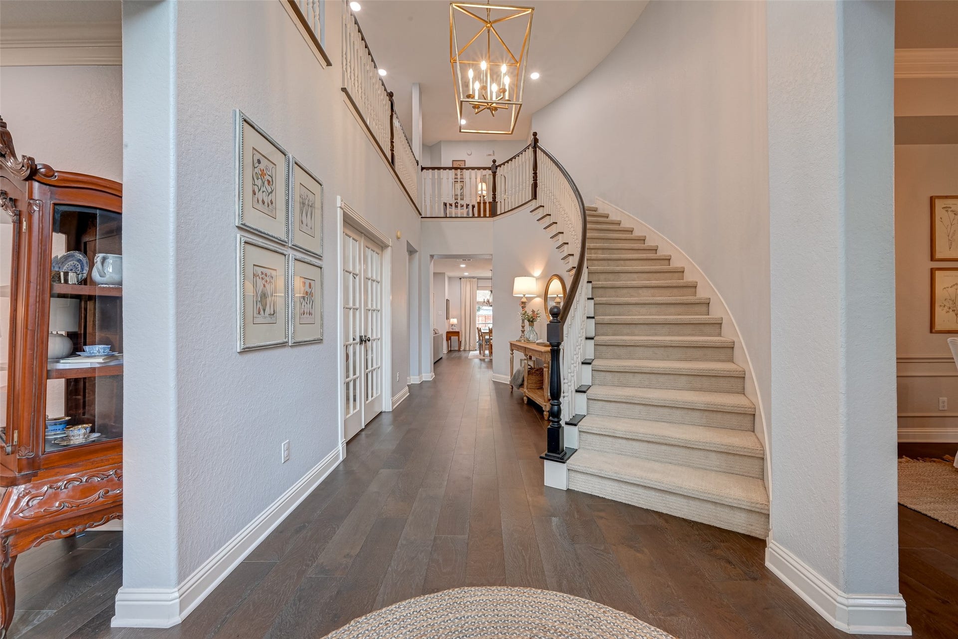 7707 Stone Arbor Drive, Sugar Land, TX 77479 The dramatic two-story foyer makes a grand impression the moment you walk in the door. The elegant curved staircase sweeps to the second floor beneath a statement chandelier, creating a beautiful architectural focal point. Matte-finished wood floors carry your eye toward the heart of the home, while French doors open to the study and formal living and dining spaces flank the entry. Classic, gracious, and full of character. Its the kind of entrance that makes you want to stop and take it all in!