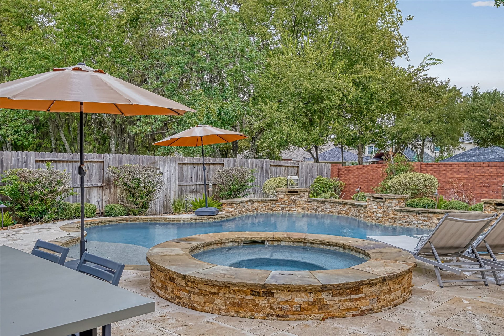 7707 Stone Arbor Drive, Sugar Land, TX 77479 Time to unwind! The raised spa takes center stage in this view, surrounded by beautiful stacked-stone detailing and the spacious Travertine deck. Whether soaking in the spa, cooling off in the pool or simply relaxing poolside, this backyard was designed to be enjoyed. Multiple waterfalls add both movement & ambiance to the setting.