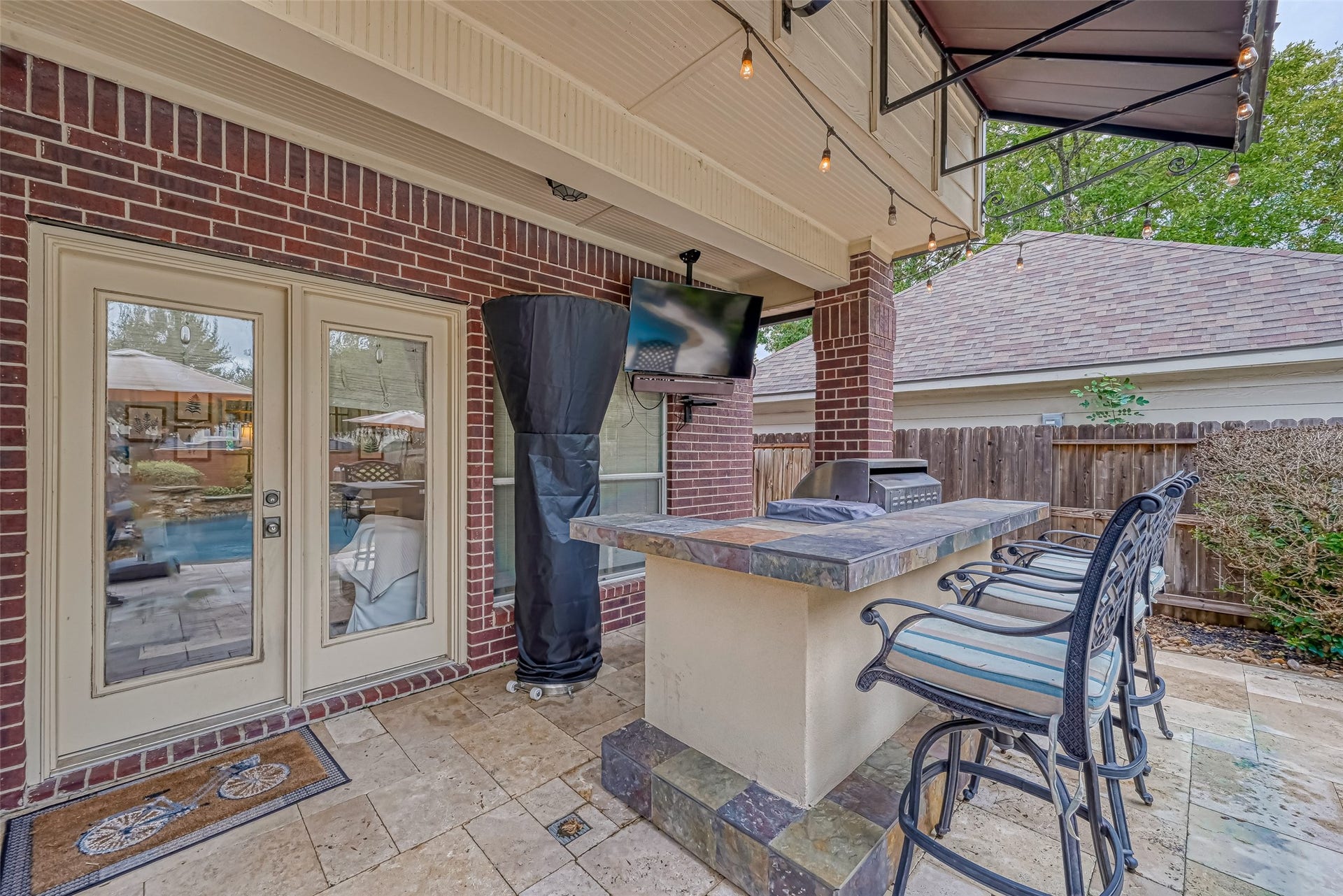 7707 Stone Arbor Drive, Sugar Land, TX 77479 Take the party outside! French doors from the family room open directly to the covered patio & outdoor kitchen, creating an easy flow for entertaining. Pull up a stool at the tiled bar, catch the game on the outdoor TV or fire up the gas grillall beneath a distinctive copper awning. Travertine decking continues into the backyard, where the pool & spa are just steps away.