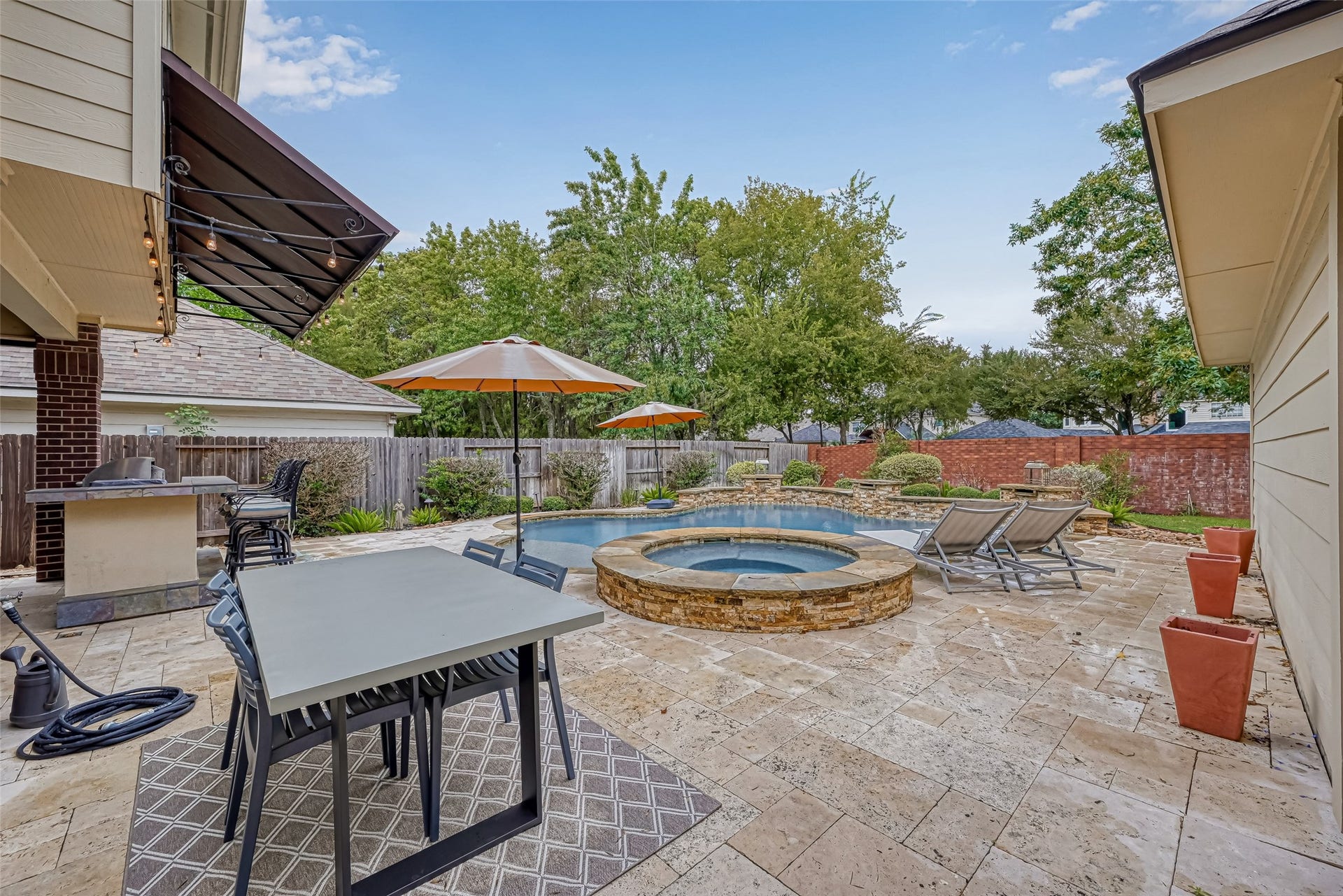 7707 Stone Arbor Drive, Sugar Land, TX 77479 Theres room for everyone out here! An expansive Travertine deck surrounds the pool & spa with plenty of space for outdoor dining, lounging, sunning & entertaining. The covered outdoor kitchen is just steps away, creating one connected outdoor living space thats ready for pool parties, family cookouts or a quiet weekend at home.