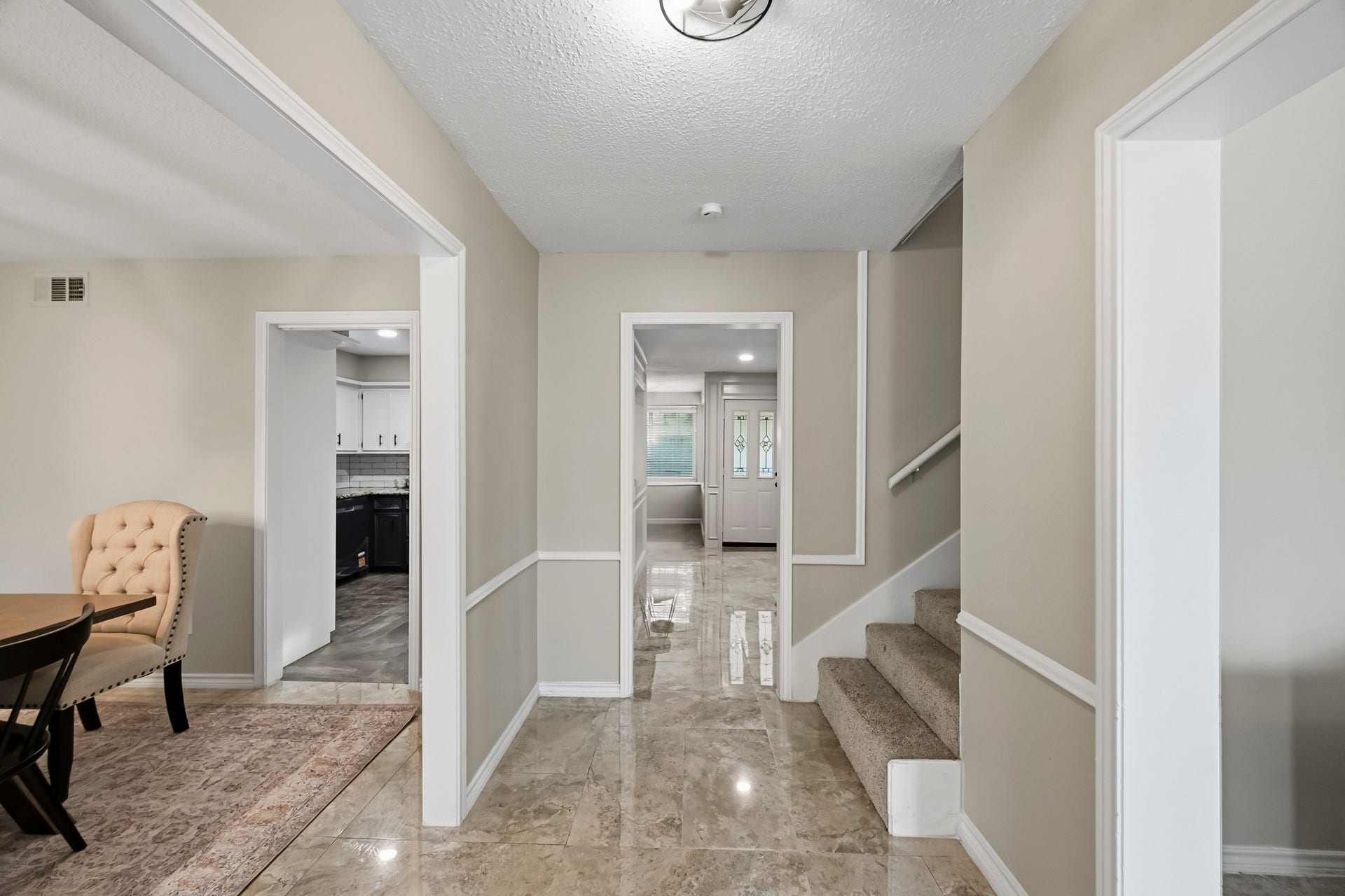 6714 Brittany Park Lane, Houston, TX 77066 Elegant entryway with gleaming tile floors, leading to a bright living area and cozy carpeted staircase. Adjacent dining room and modern kitchen offer seamless flow for entertaining.