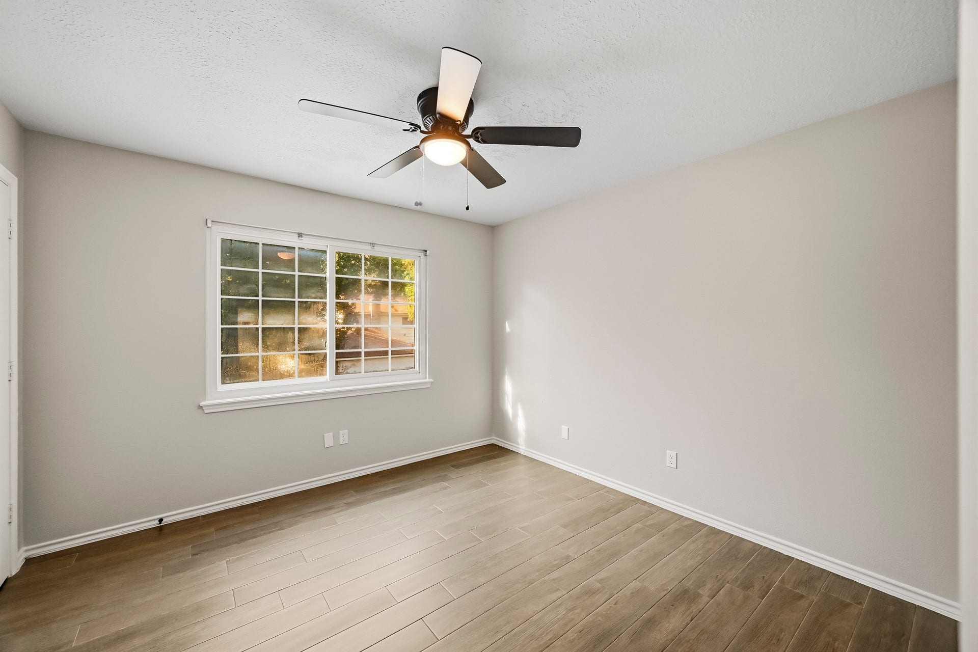 6714 Brittany Park Lane, Houston, TX 77066 Bright and inviting room with sleek wood-look flooring, a modern ceiling fan, and a large window that fills the space with natural light.