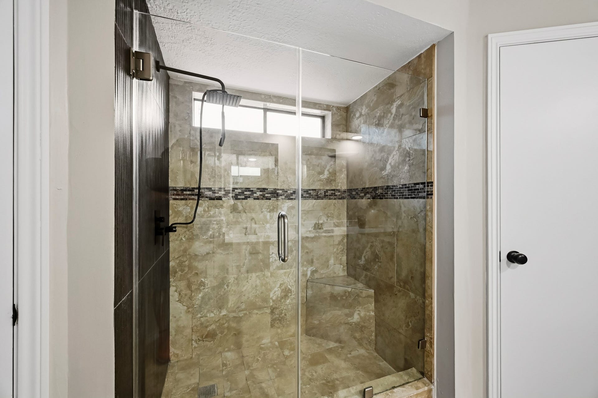 6714 Brittany Park Lane, Houston, TX 77066 Luxurious walk-in shower with elegant tile work, a modern rain showerhead, and glass doors, offering a spa-like experience.