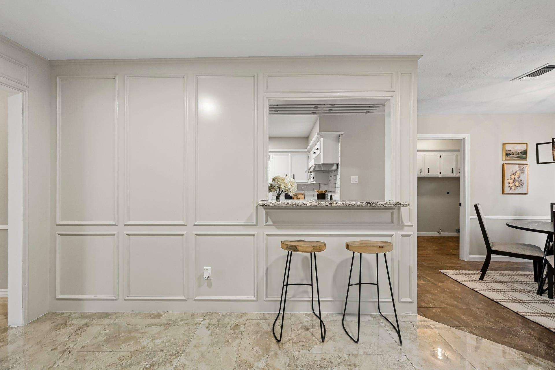 6714 Brittany Park Lane, Houston, TX 77066 Elegant open-concept space featuring a chic breakfast bar with stylish stools, framed by classic paneling and leading to a bright kitchen area.