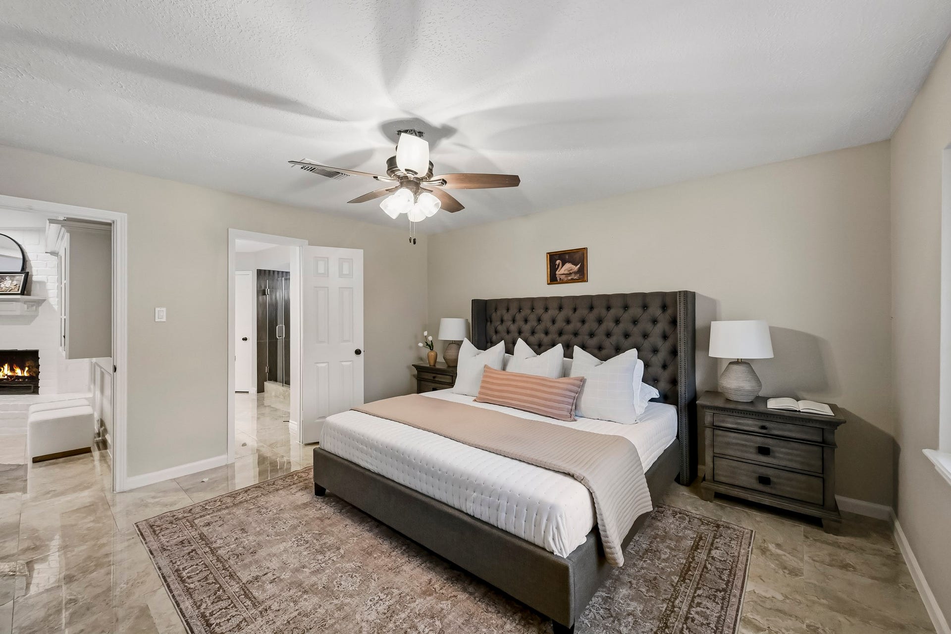 6714 Brittany Park Lane, Houston, TX 77066 Spacious bedroom featuring a luxurious bed with a tufted headboard, elegant nightstands, and a cozy ambiance enhanced by a ceiling fan.