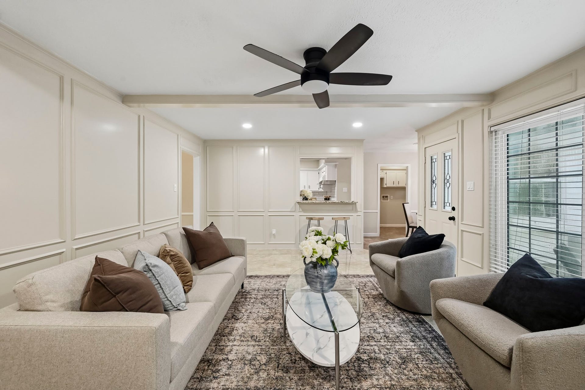6714 Brittany Park Lane, Houston, TX 77066 Elegant living area with neutral tones, featuring a cozy seating arrangement, modern ceiling fan, and large windows for natural light.