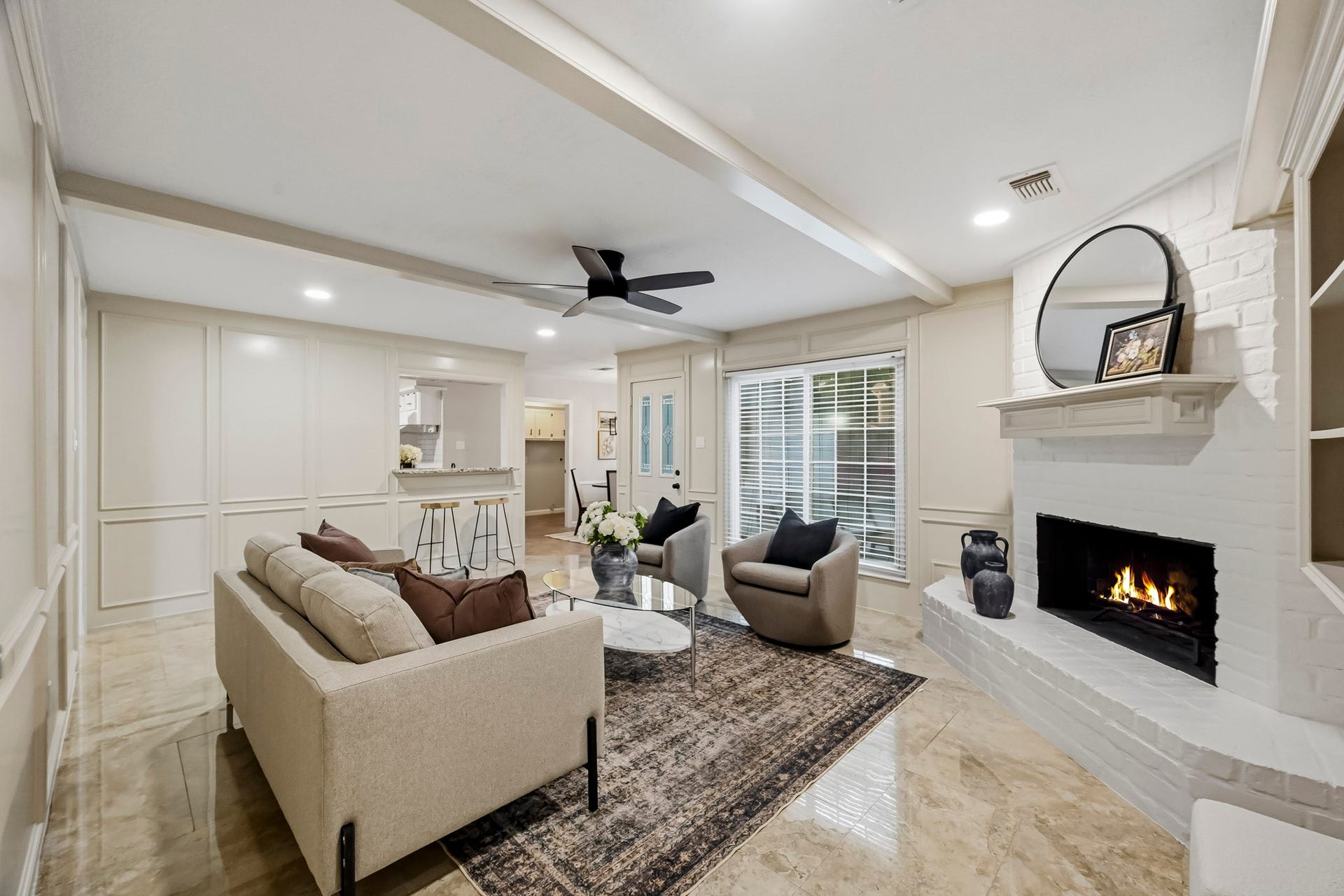 6714 Brittany Park Lane, Houston, TX 77066 Inviting living room with a cozy fireplace, elegant ceiling beams, and ample natural light from large windows.