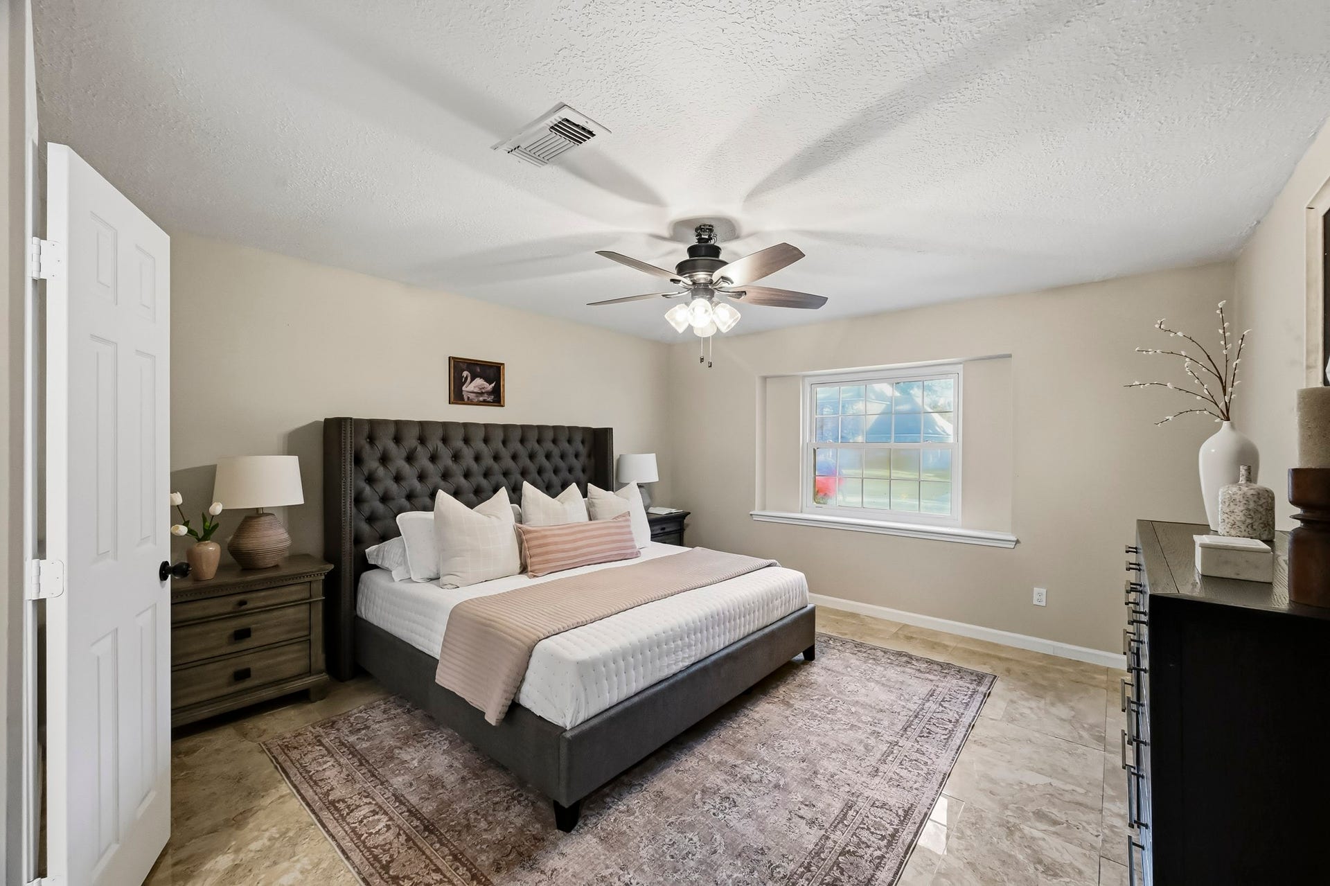 6714 Brittany Park Lane, Houston, TX 77066 Spacious bedroom featuring a plush, tufted bed and elegant dcor, with a large window allowing natural light to enhance the warm, welcoming atmosphere.