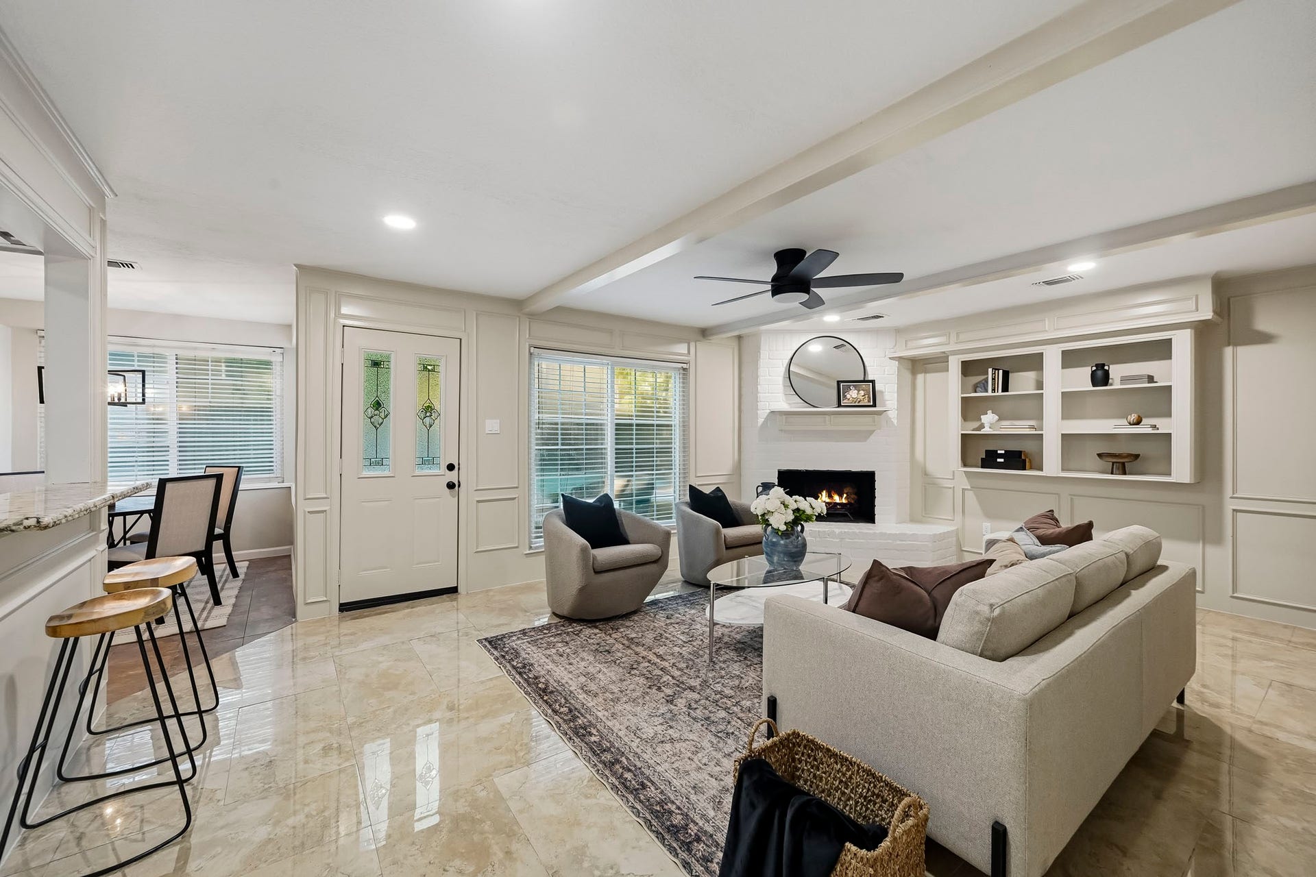 6714 Brittany Park Lane, Houston, TX 77066 Spacious living area with elegant marble floors, a cozy fireplace, and custom built-in shelving, seamlessly connected to a dining nook through a granite breakfast bar.