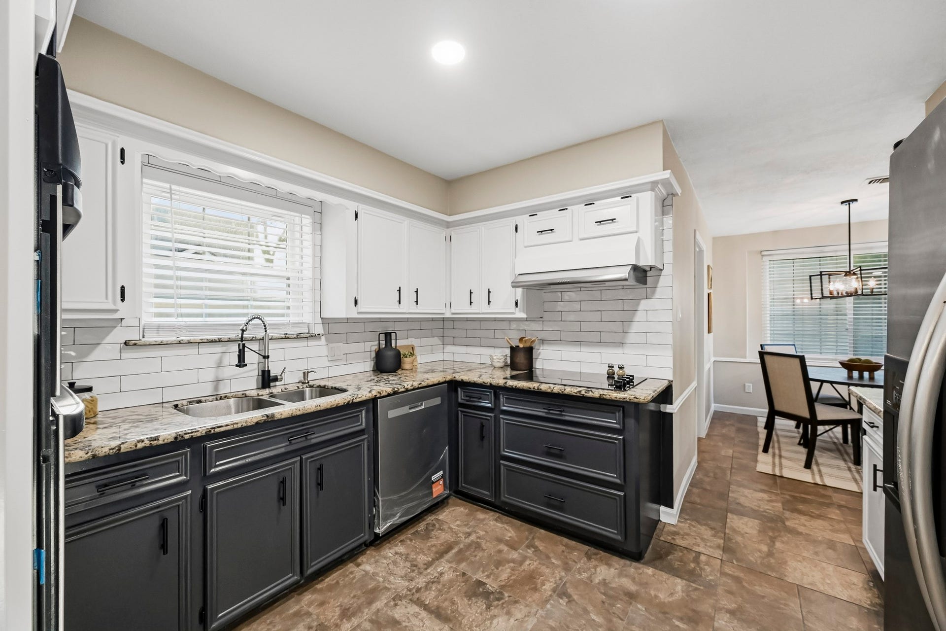 6714 Brittany Park Lane, Houston, TX 77066 Charming kitchen with a sleek black-and-white color scheme, granite countertops, and modern stainless steel appliances, seamlessly connecting to a cozy dining area.
