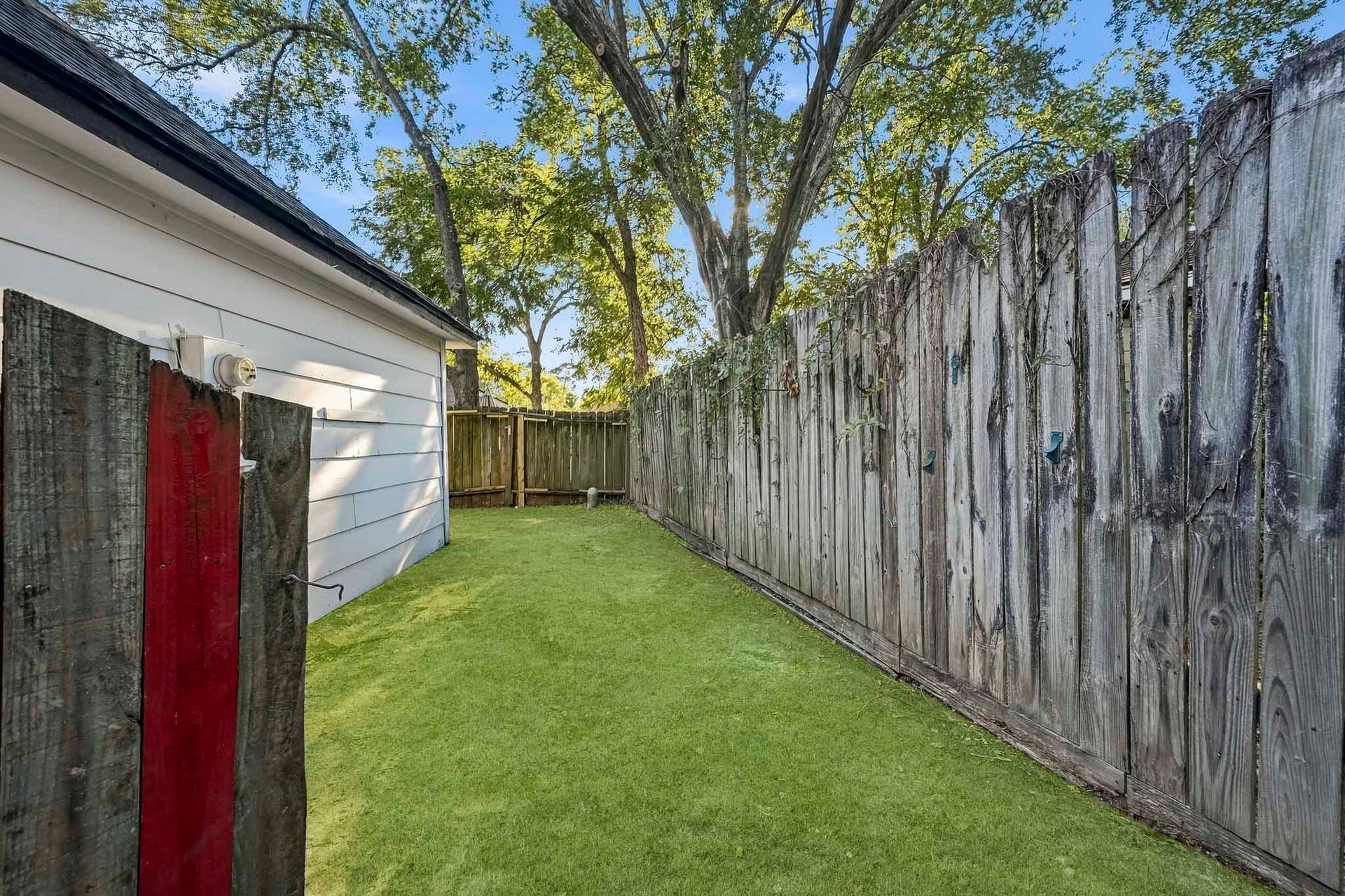 6714 Brittany Park Lane, Houston, TX 77066 Charming backyard space with lush green lawn, bordered by a classic wooden fence, perfect for outdoor relaxation or gardening.