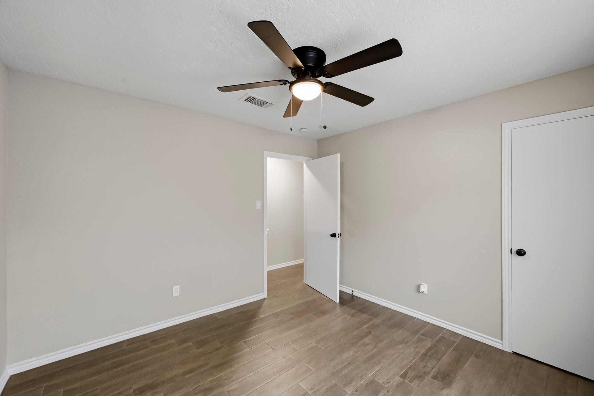 6714 Brittany Park Lane, Houston, TX 77066 Bright and inviting bedroom featuring sleek wooden floors, a modern ceiling fan, and neutral walls for a serene atmosphere.