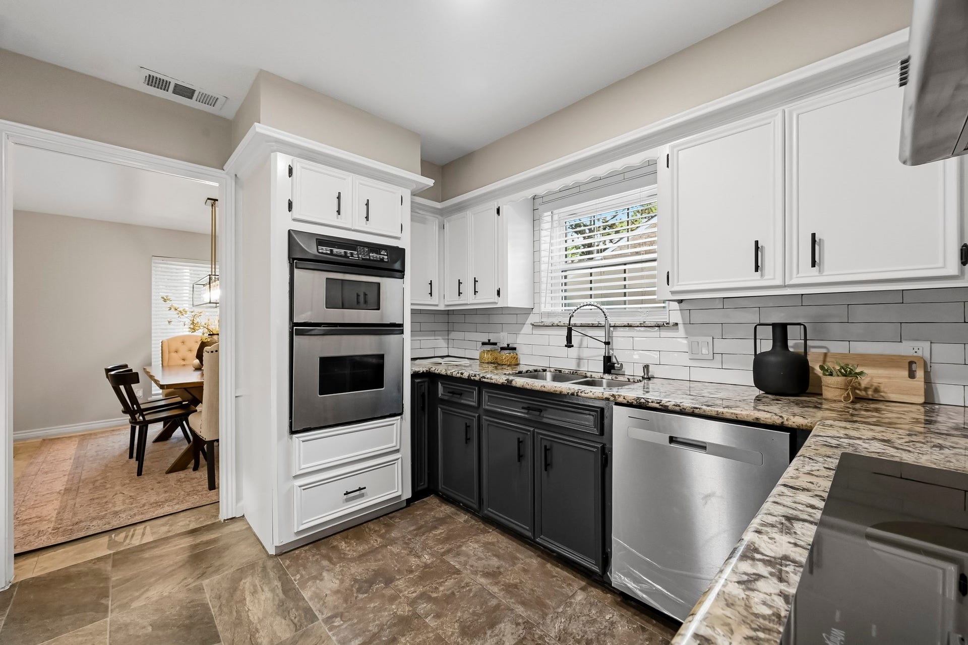 6714 Brittany Park Lane, Houston, TX 77066 Stylish kitchen with modern stainless steel appliances, dual-tone cabinetry, and granite countertops, seamlessly leading to a cozy dining area.