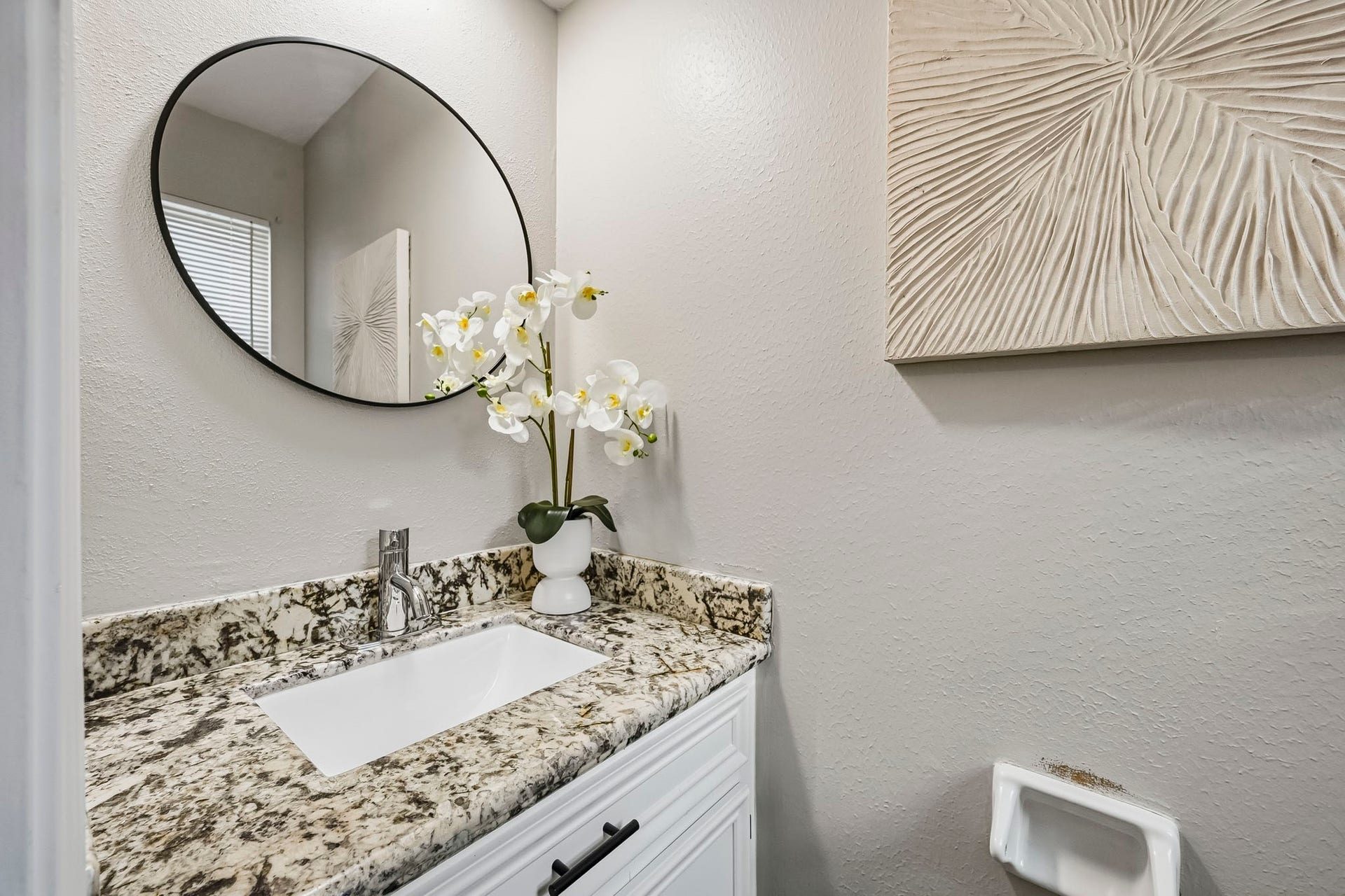6714 Brittany Park Lane, Houston, TX 77066 Chic and modern bathroom featuring a sleek granite countertop, elegant oval mirror, and stylish contemporary decor, offering a serene and sophisticated ambiance.