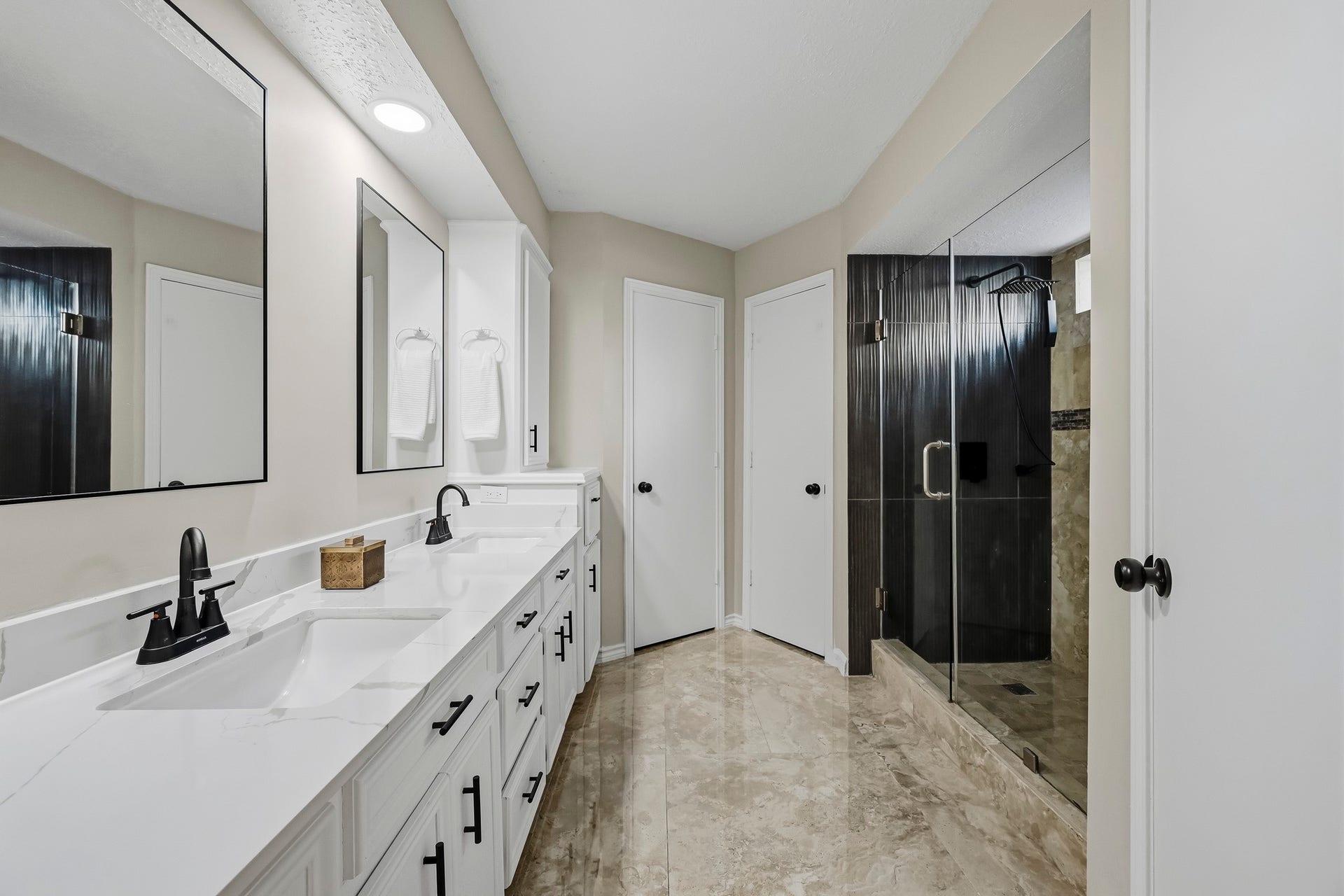6714 Brittany Park Lane, Houston, TX 77066 Elegant bathroom featuring a spacious double vanity with sleek black fixtures, complemented by a luxurious glass-enclosed shower and ample storage.