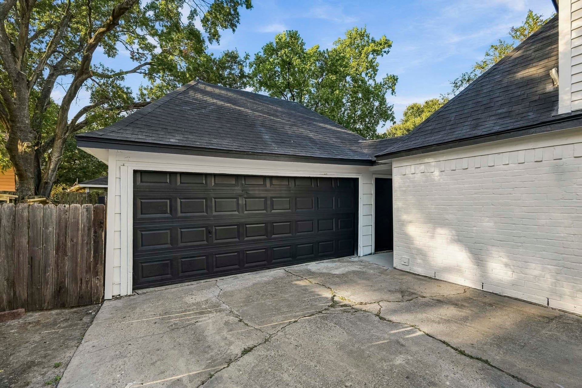 6714 Brittany Park Lane, Houston, TX 77066 Spacious two-car garage with a sleek black door, set against a charming white brick exterior, offering easy access and ample driveway space.