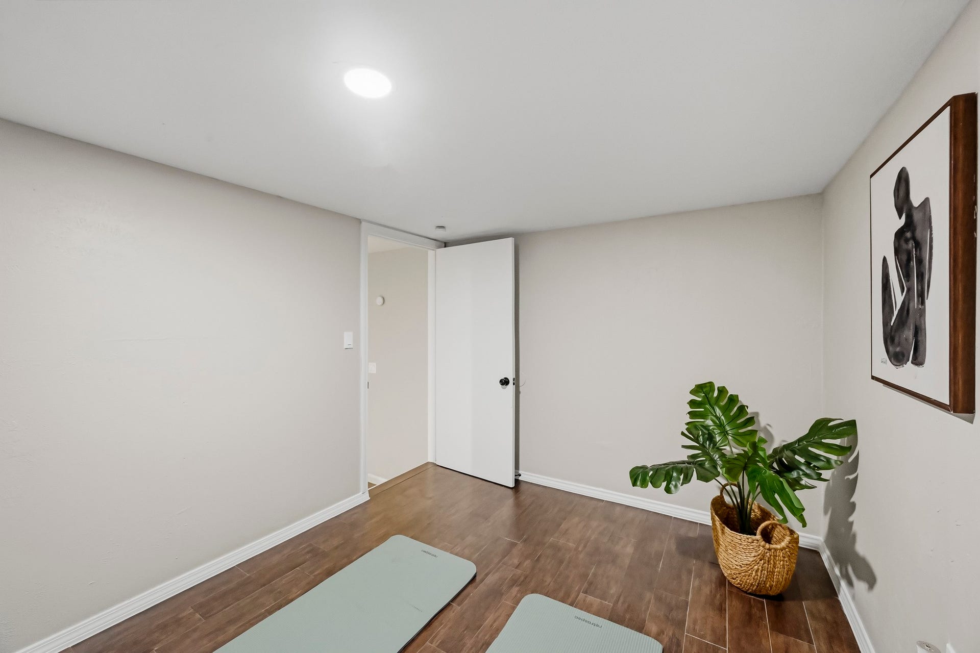 6714 Brittany Park Lane, Houston, TX 77066 Bright and inviting space with hardwood floors, perfect for a home gym or relaxation area, accented by a modern art piece and lush greenery.