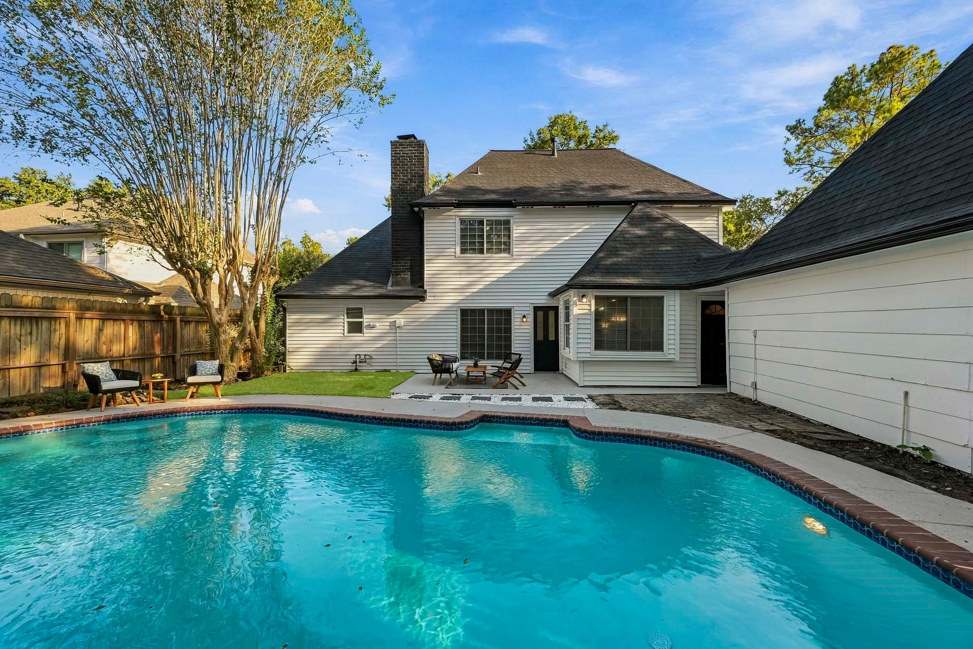 6714 Brittany Park Lane, Houston, TX 77066 Charming two-story home with a spacious backyard featuring a sparkling pool, surrounded by mature trees and a cozy patio area perfect for relaxation and entertaining.