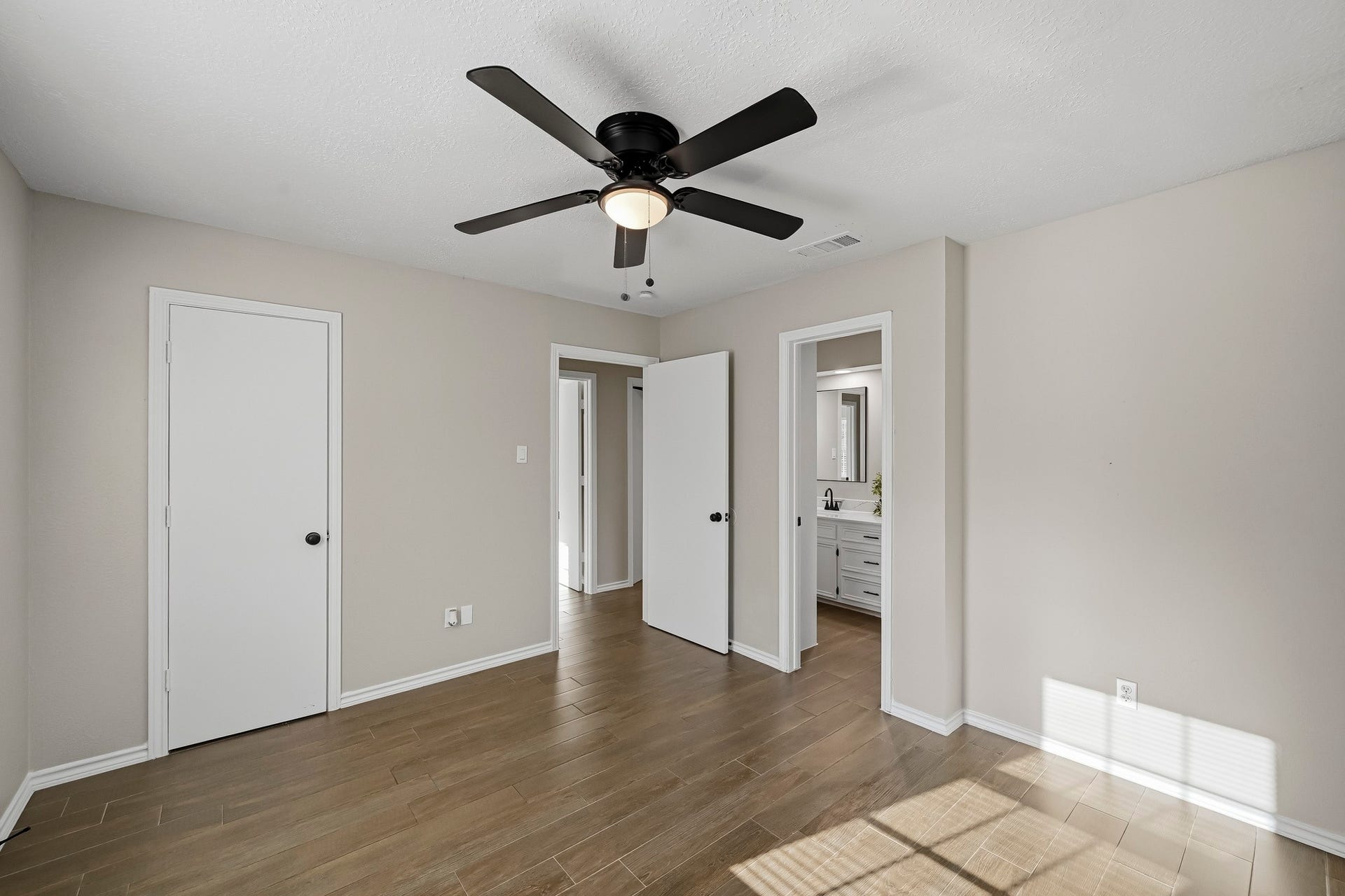 6714 Brittany Park Lane, Houston, TX 77066 Bright and airy room featuring sleek wood flooring, a modern ceiling fan, and direct access to a stylish bathroom.