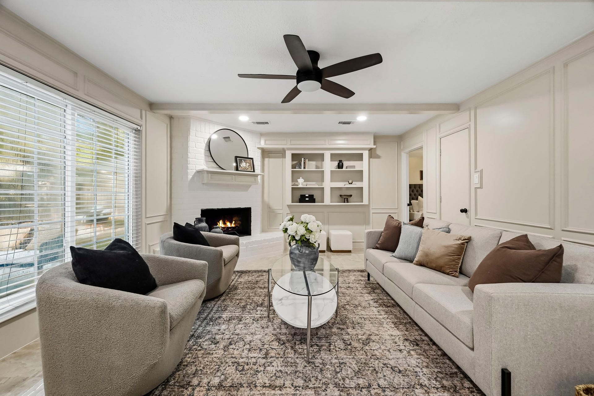 6714 Brittany Park Lane, Houston, TX 77066 Elegant living room featuring a cozy fireplace, built-in shelving, and abundant natural light, perfect for relaxation and entertaining.