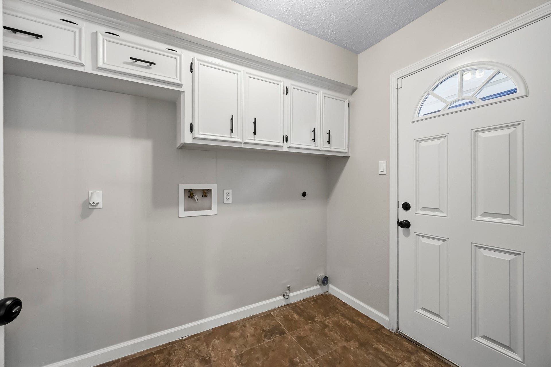 6714 Brittany Park Lane, Houston, TX 77066 Bright and functional laundry room with ample cabinet storage and convenient utility hookups, complemented by a classic door design.