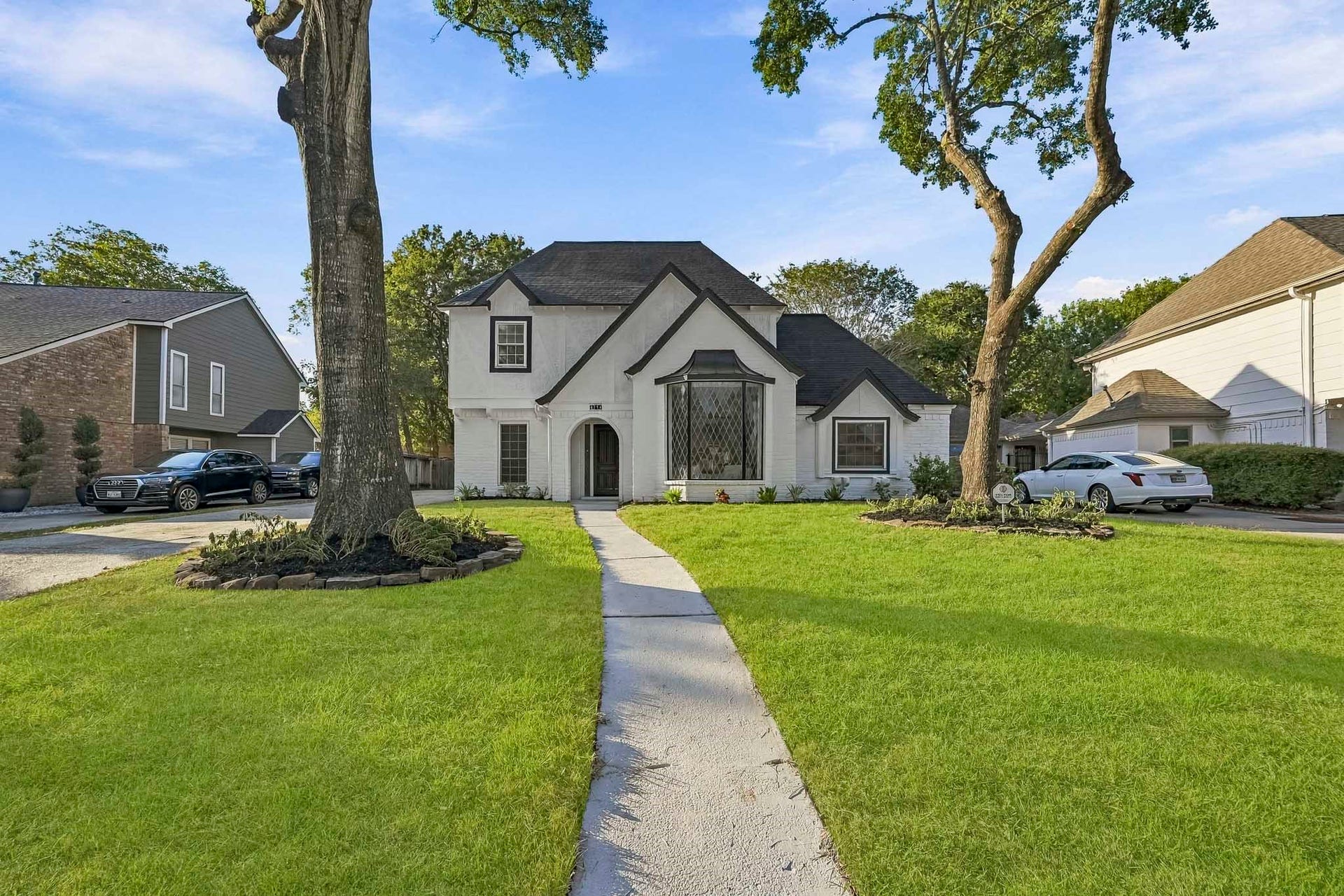 6714 Brittany Park Lane, Houston, TX 77066 Charming two-story home with a classic black and white exterior, nestled between mature trees and featuring a welcoming arched entrance.