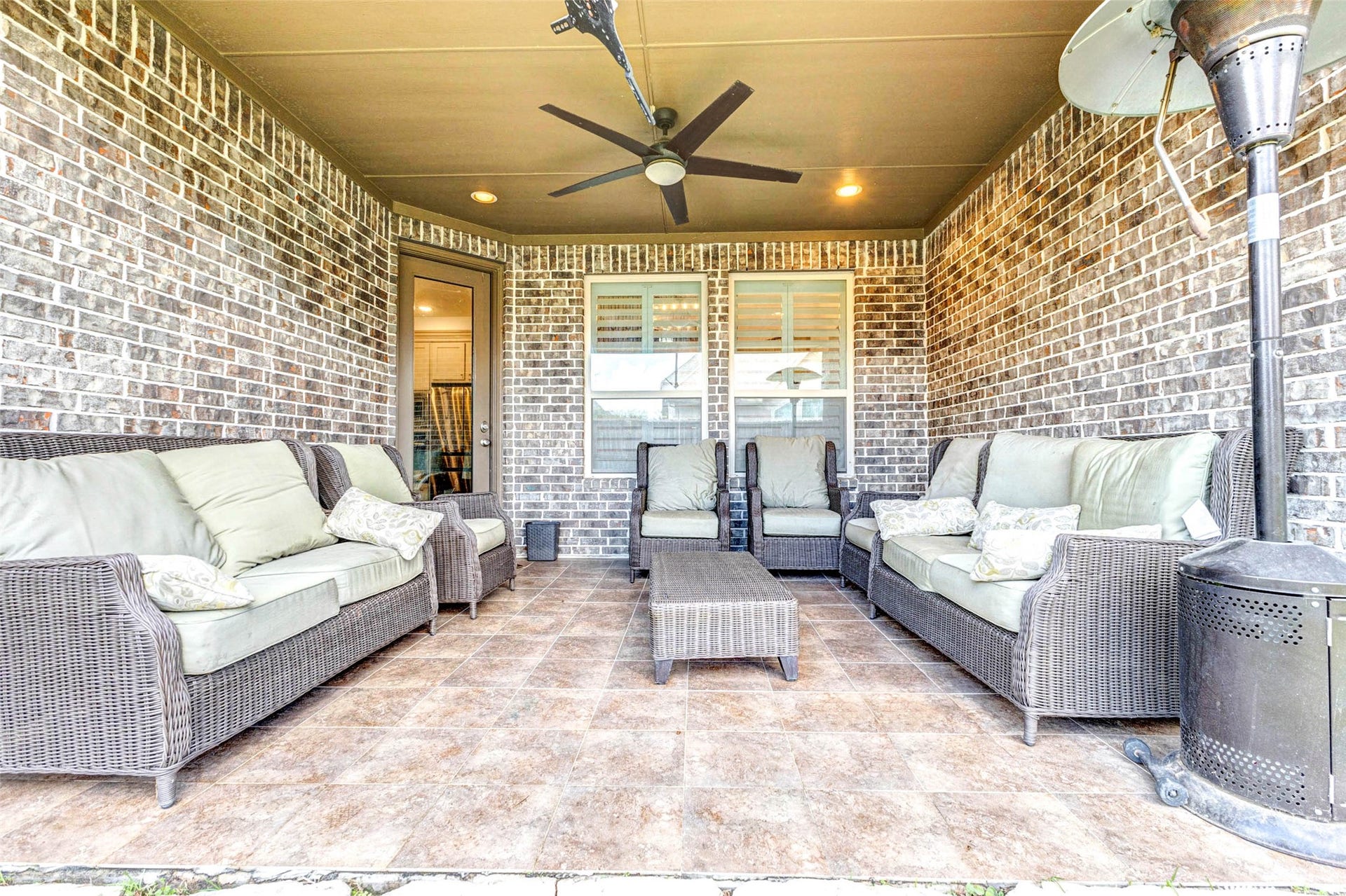 Enjoy outdoor living year-round on this covered patio, complete with ample seating space and a ceiling fan for added comfort. The brick surround adds character, while the shaded setting makes it perfect for relaxing or entertaining. Whether hosting guests or enjoying a quiet evening, this inviting outdoor space extends your living area beautifully.