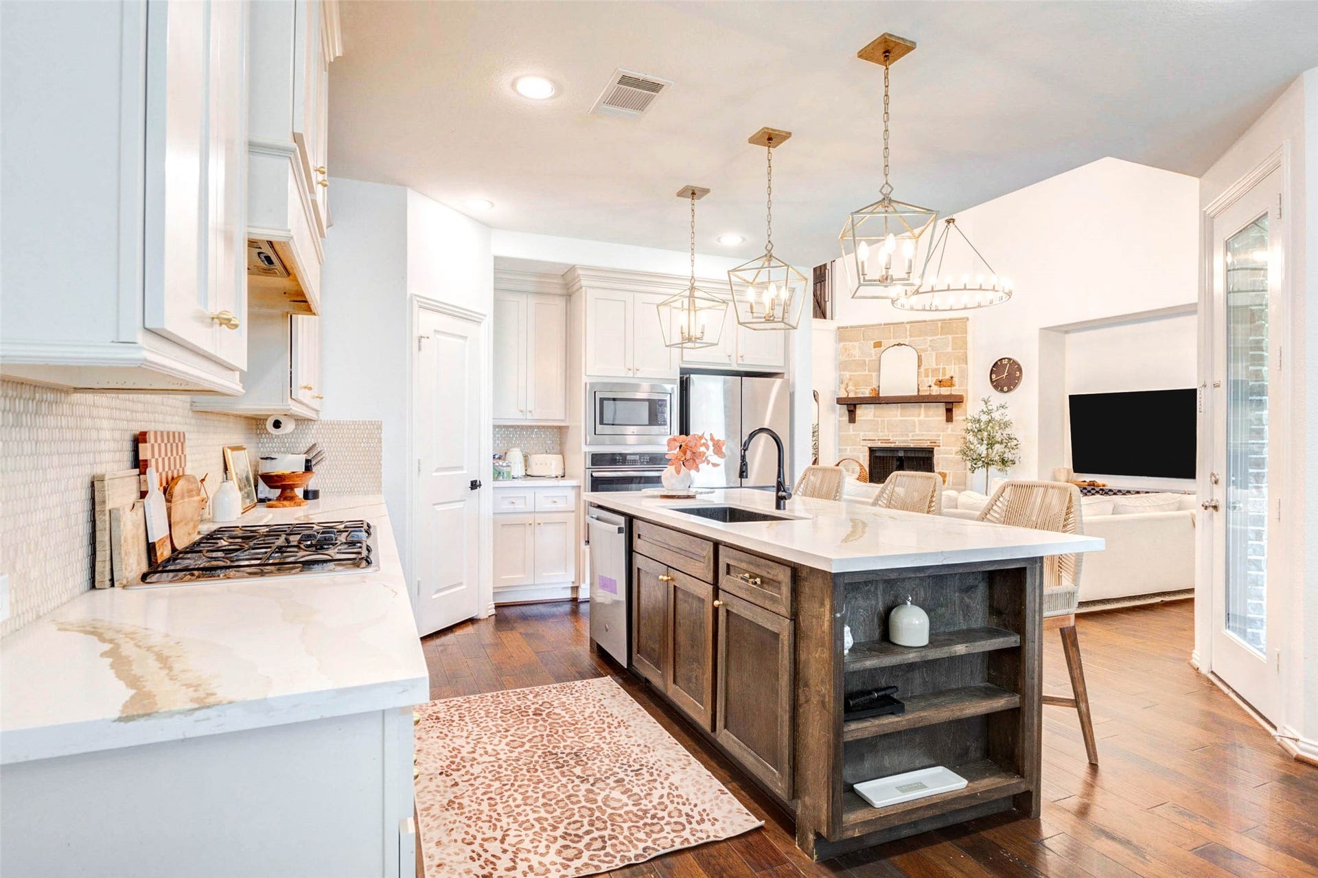 Enjoy seamless indoor living with this open kitchen that overlooks the main living area, allowing for effortless interaction and entertaining. The spacious island anchors the space, while pendant lighting adds warmth and style. Sightlines to the fireplace and living room create a cohesive flow, making this layout perfect for hosting gatherings or enjoying everyday life in a connected, comfortable environment.