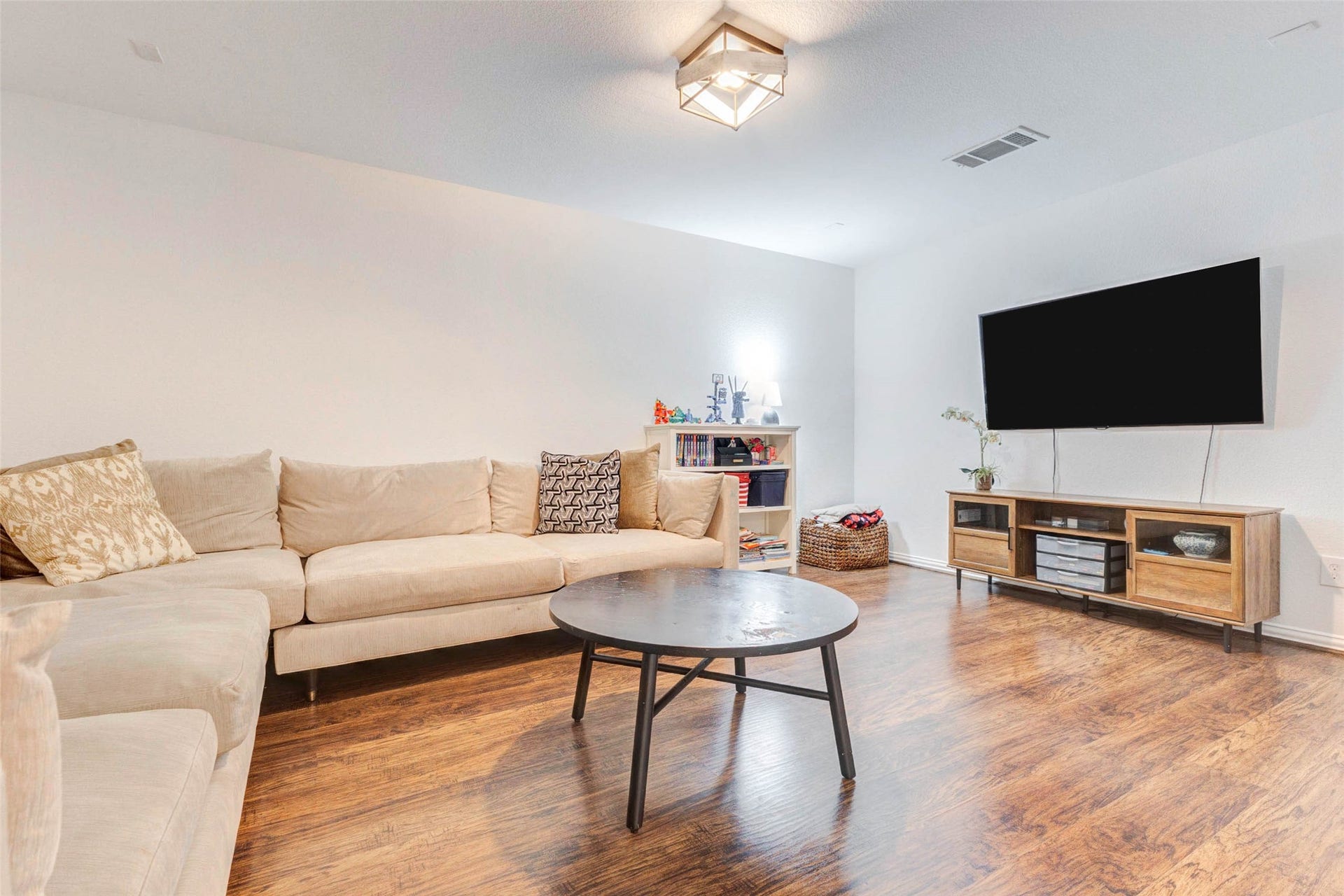 This cozy secondary living space works well as a media room, game room, or lounge. The neutral tones and warm wood flooring create an inviting atmosphere, while the open layout allows for flexible furniture arrangements. A mounted TV and additional storage make this space both practical and comfortable, offering a private retreat ideal for entertainment, gaming, or unwinding at the end of the day.