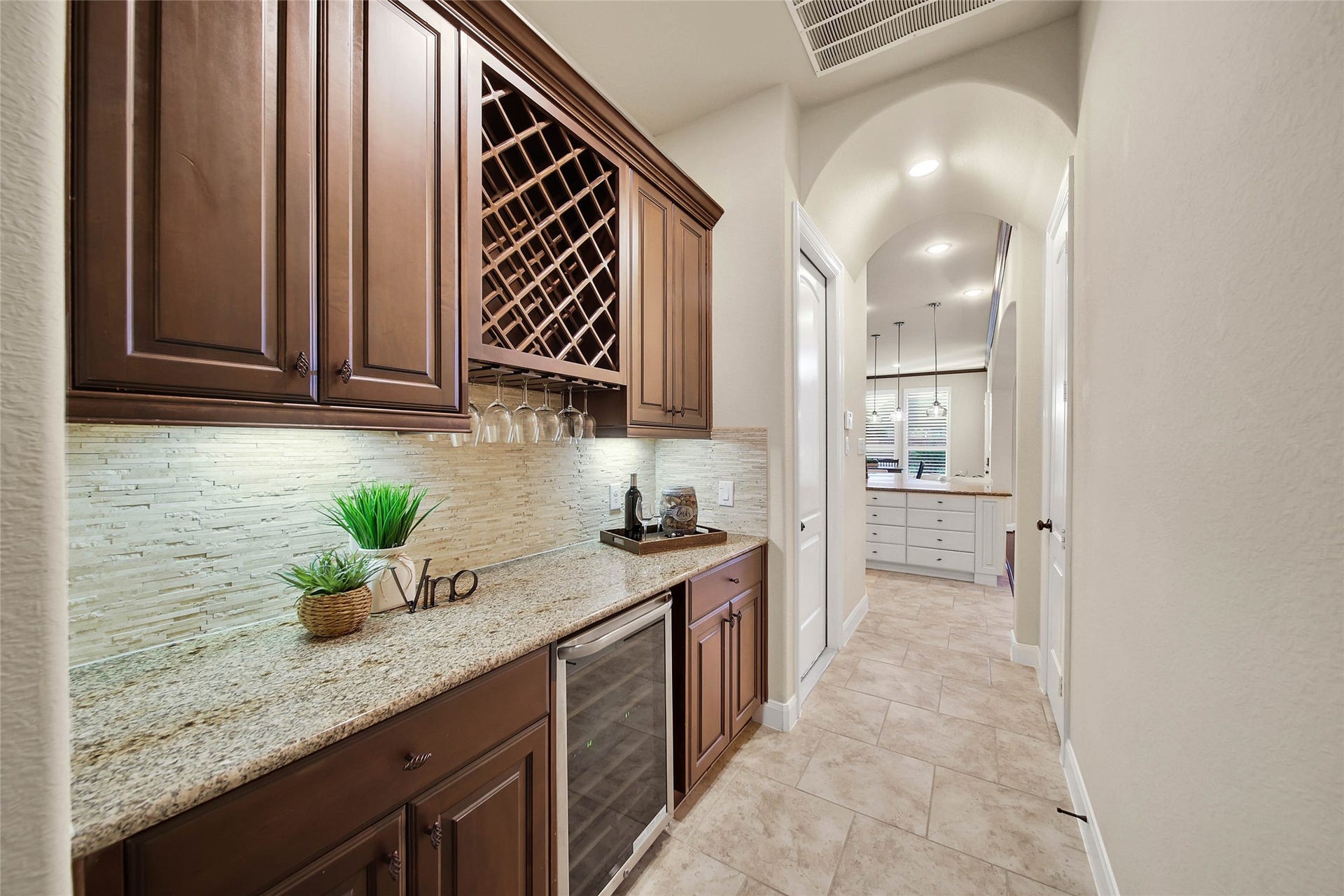 5318 Briarcliff Lane, Fulshear, TX 77441 Perfect for entertaining, the butlers pantry features upper cabinets to store barware, a built-in wine rack, and generous storage for additional china and stemware. Granite counters with travertime backsplash anchors the space, complemented by abundant lower storage and a wine chiller.