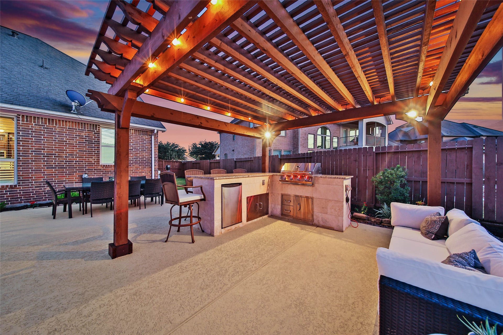 5318 Briarcliff Lane, Fulshear, TX 77441 The custom pergola creates a second covered gathering space, complete with an outdoor kitchen featuring a 2026 Kokomo grill and mini refrigerator. This inviting dining and conversation area offers yet another fabulous spot to dine al fresco plus entertain family and friends! Built-in interior lights on the Kokomo illuminate the cooking surface so you can see your food clearly while grilling at night!
