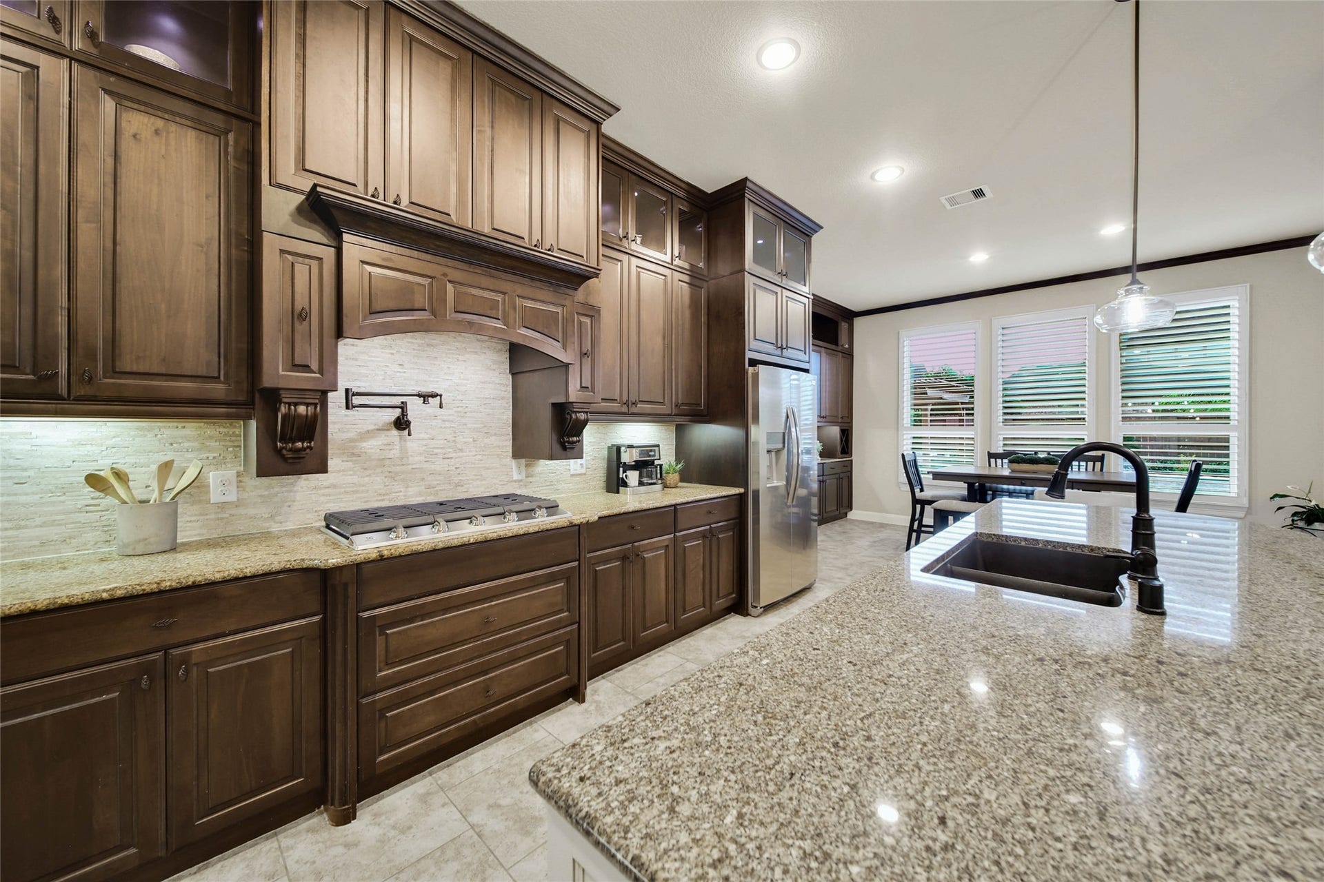 5318 Briarcliff Lane, Fulshear, TX 77441 The beautiful stacked travertine backsplash adds timeless elegance, perfectly complementing the cabinetry and countertops while elevating the kitchens overall design.