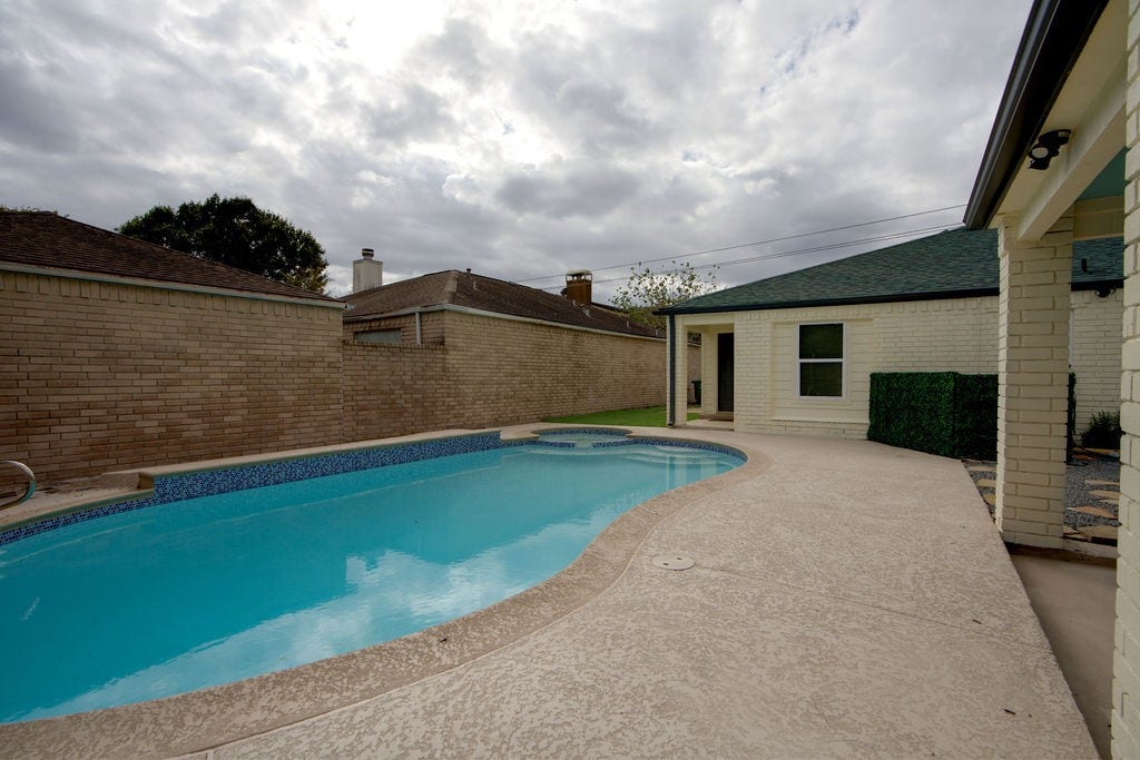 Experience serene outdoor living with this inviting backyard featuring a sparkling pool and ample patio space, perfect for relaxation and entertaining.